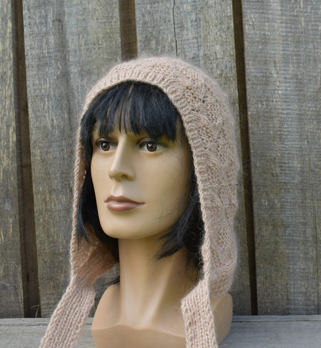 Mannequin head wearing a beige knitted hood against a wooden background