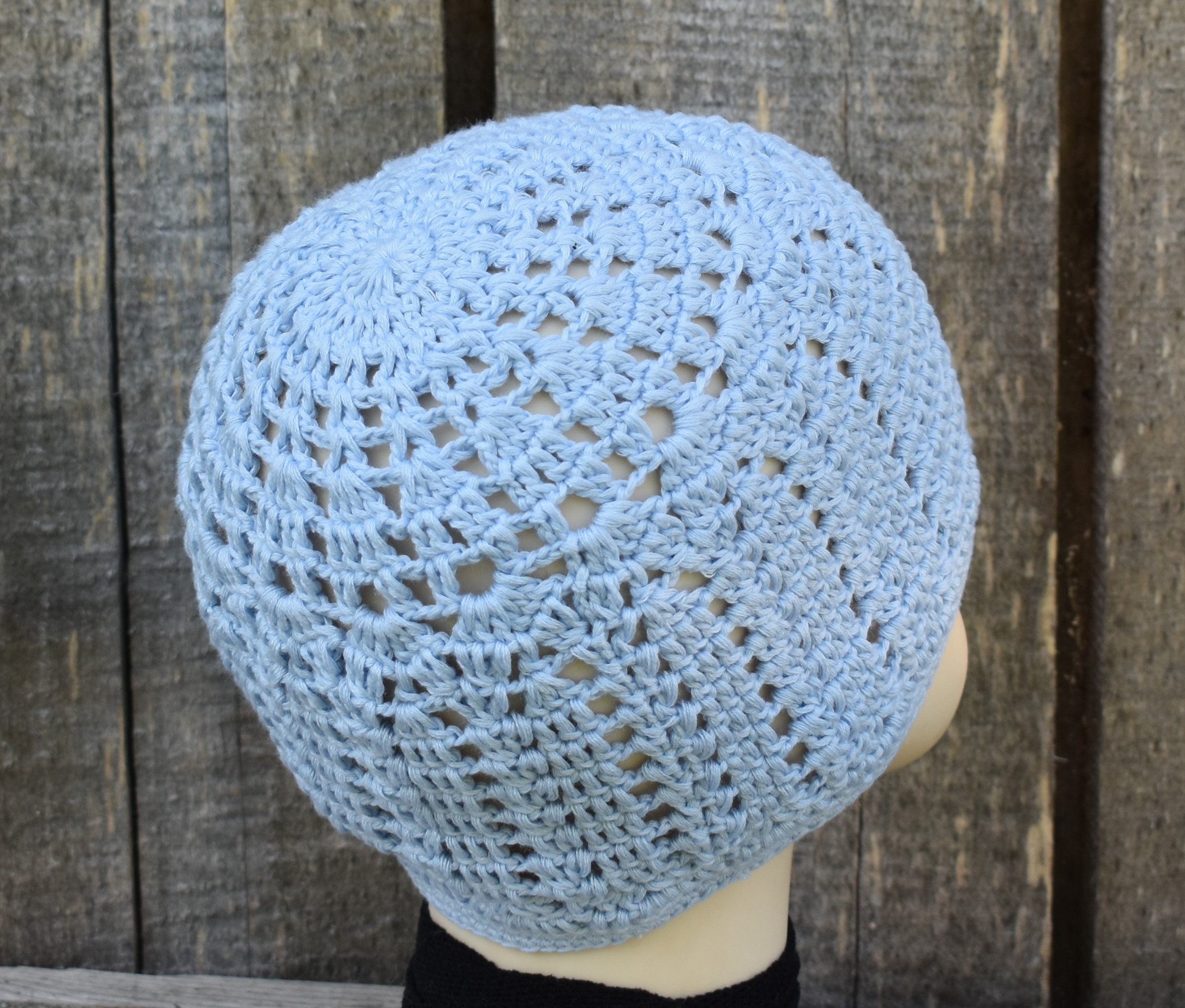 Blue crochet hat on a mannequin head against a wooden background