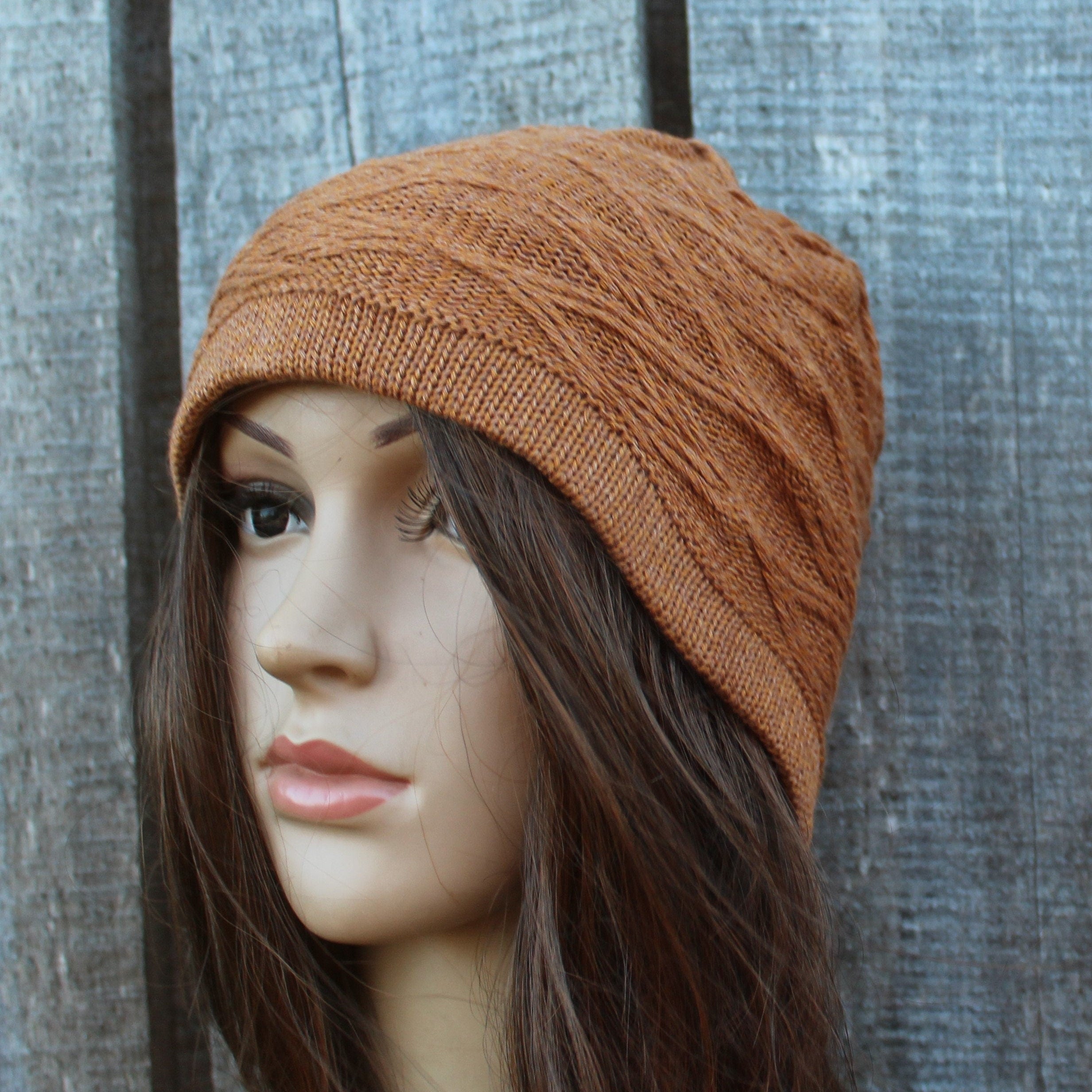 Brown knitted beanie on a mannequin head against a wooden background