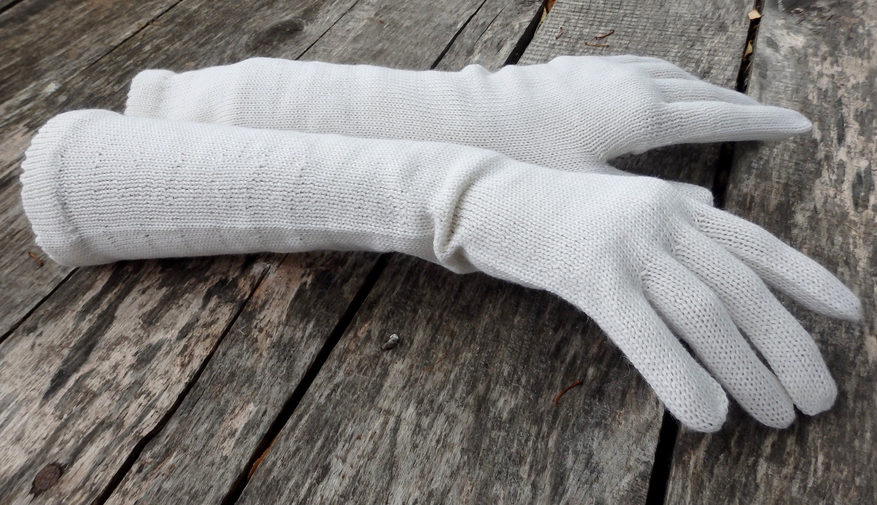 Pair of white gloves on a wooden surface