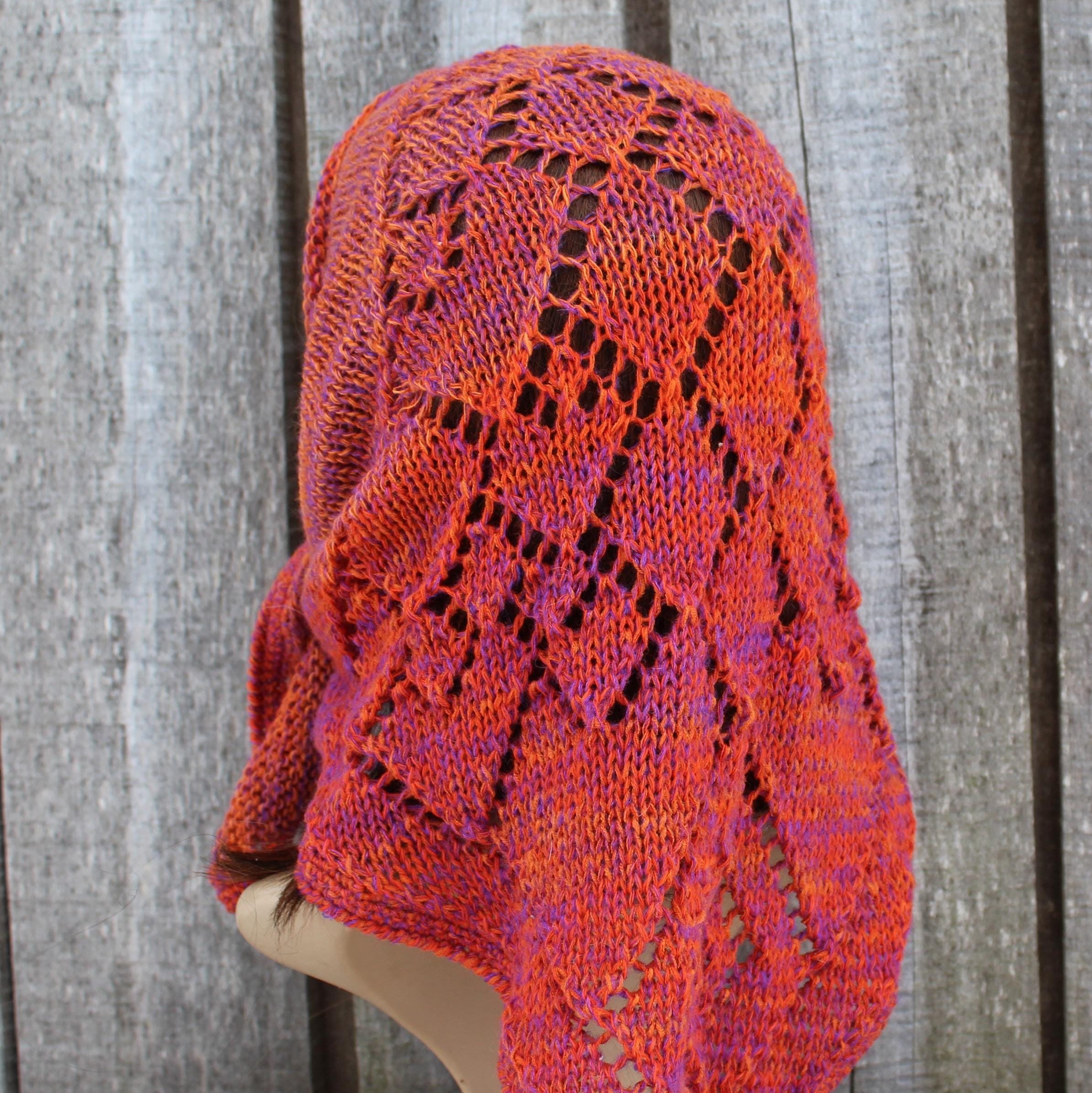 Knitted shawl with a lace pattern draped over a mannequin against a wooden background