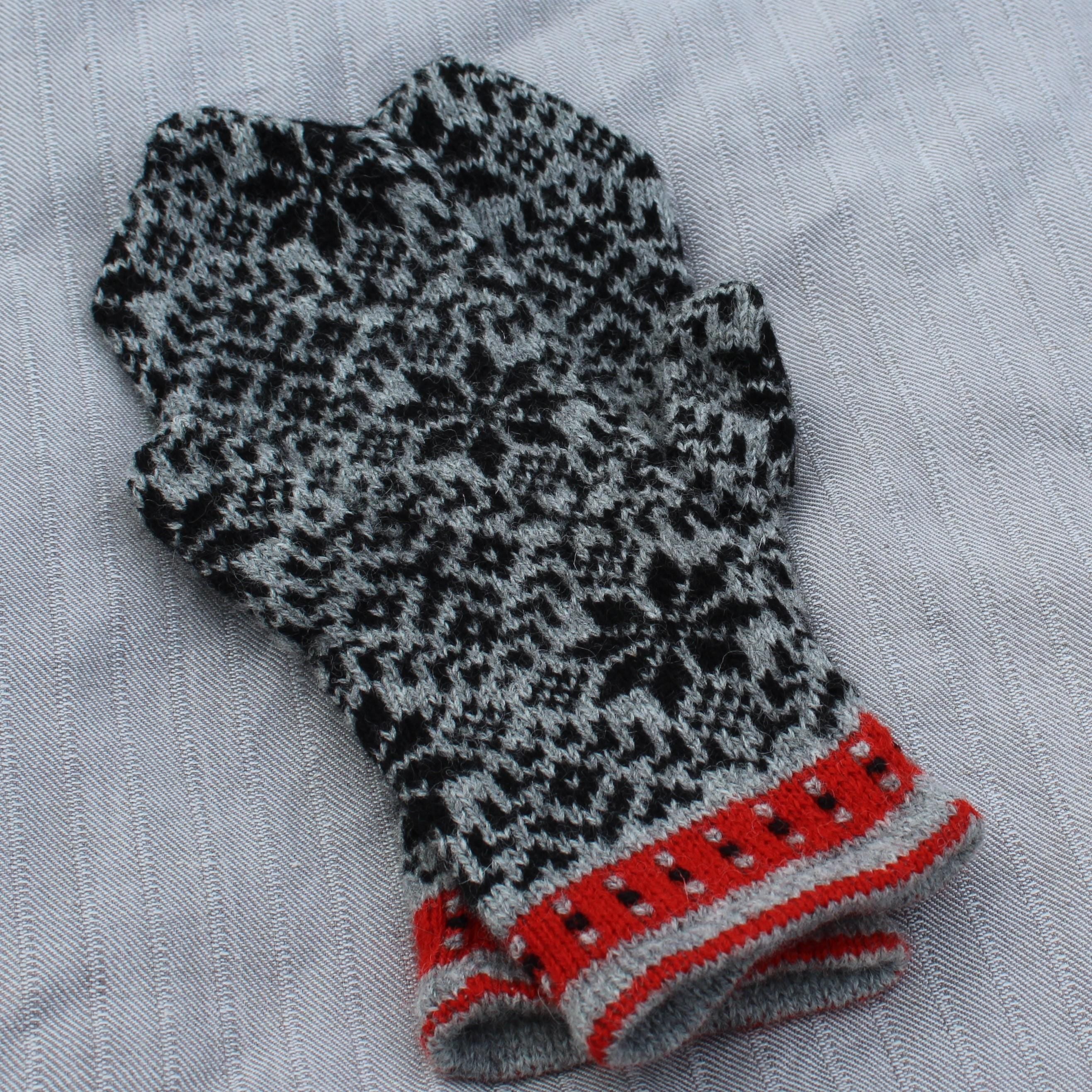 Knitted mitten with a pattern on a textured fabric background