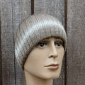 Mannequin head wearing a knitted beanie against a wooden background