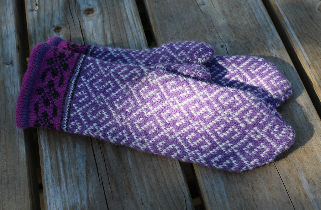 Pair of purple and white patterned mittens on a wooden surface