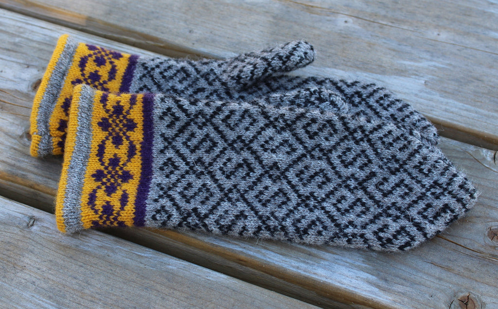 Pair of gray and yellow patterned mittens on a wooden surface