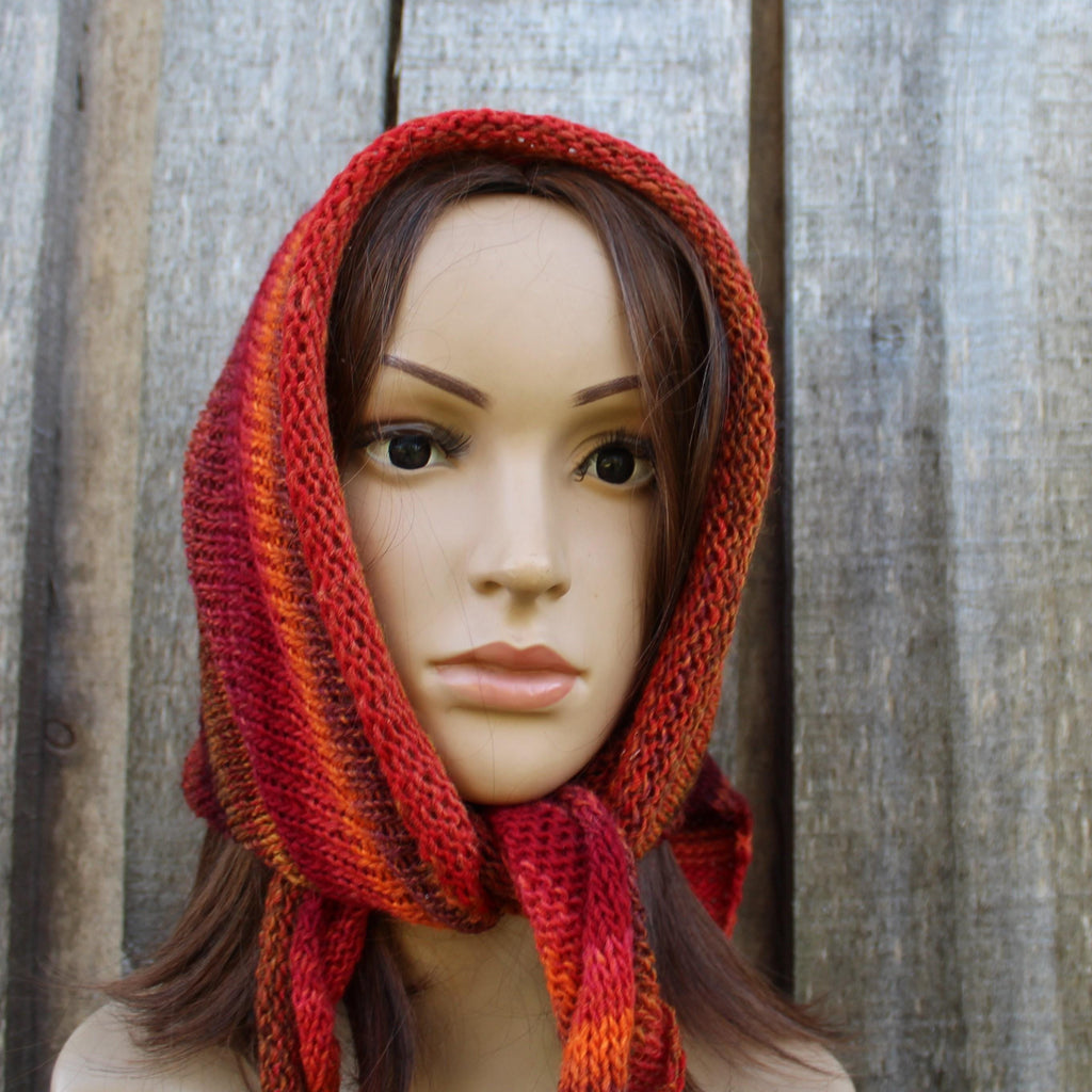 Mannequin wearing a red and orange striped knitted bonnet against a wooden background