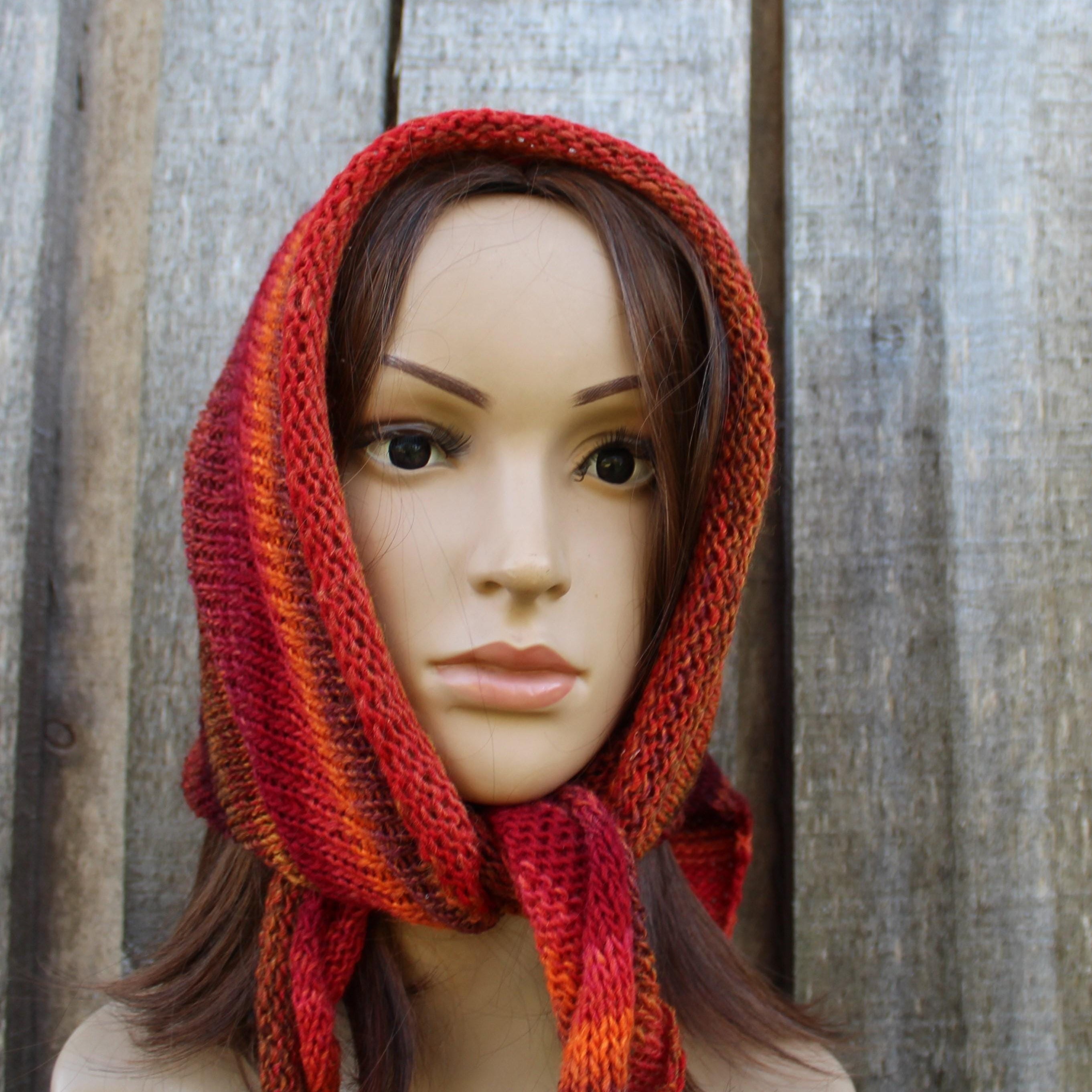 Mannequin wearing a red and orange striped knitted bonnet against a wooden background