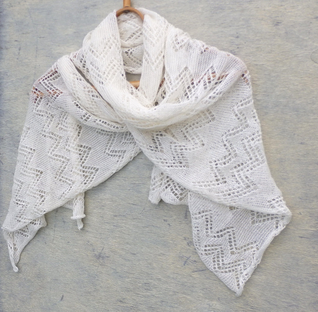 White lace shawl on a wooden hanger against a gray background