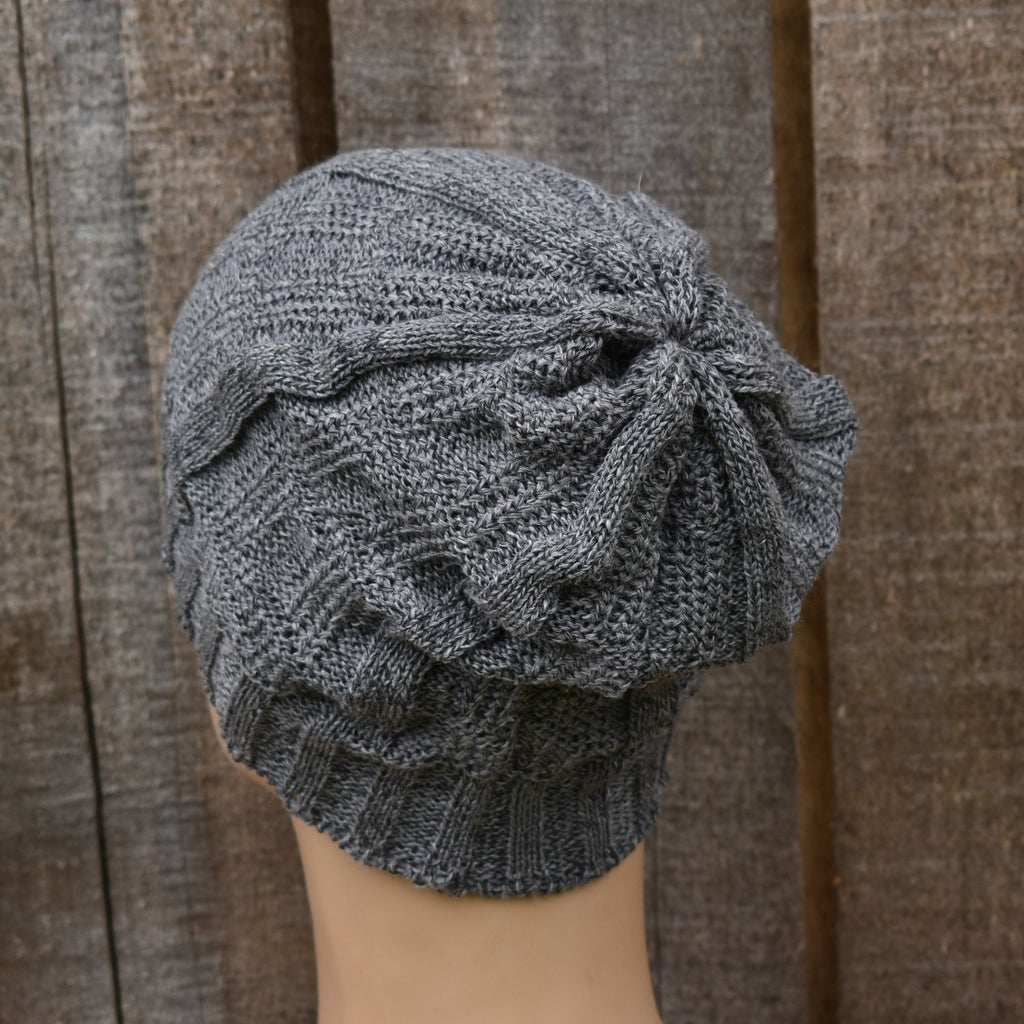Gray knit hat on a mannequin head against a wooden background