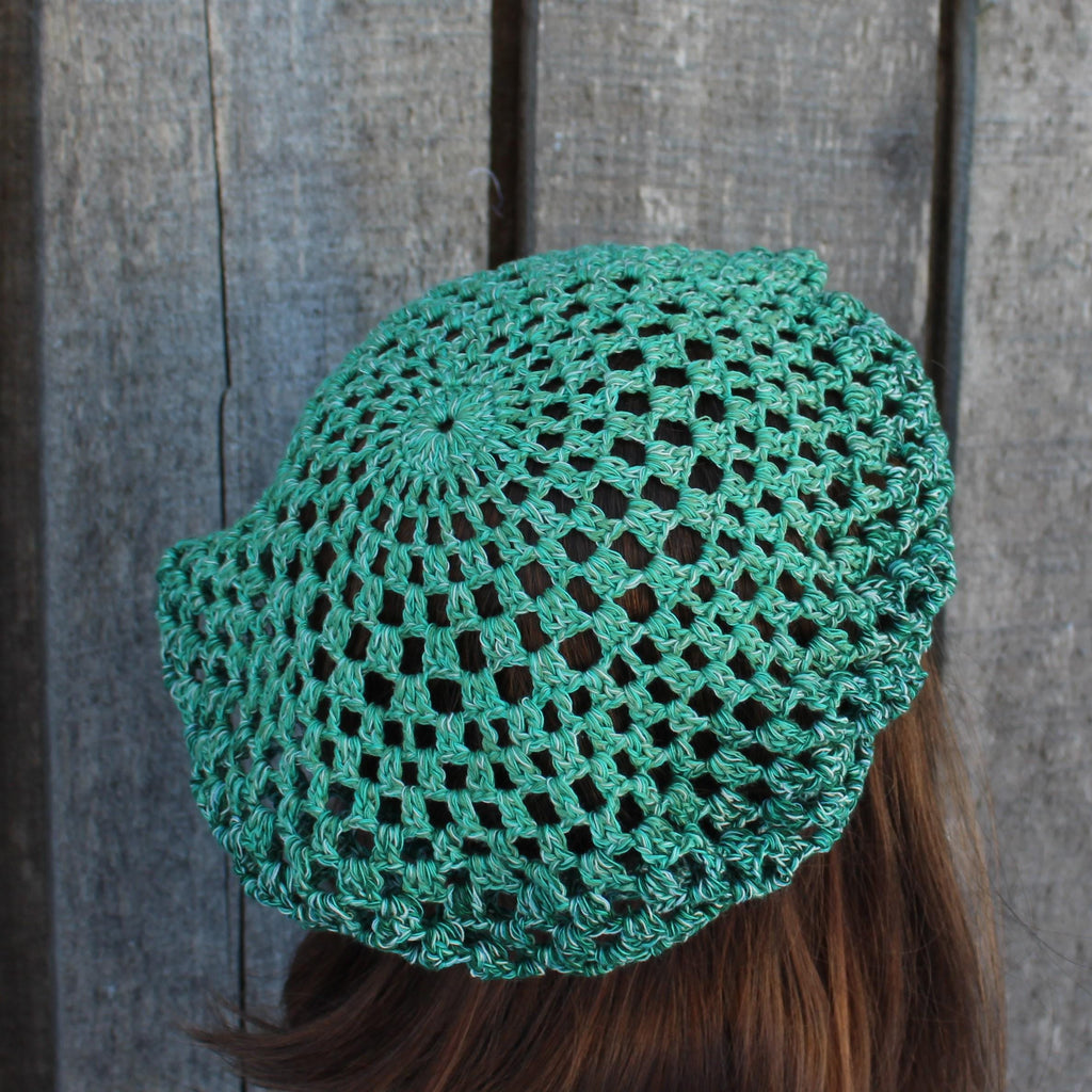 Green crocheted  worn by a person against a wooden background