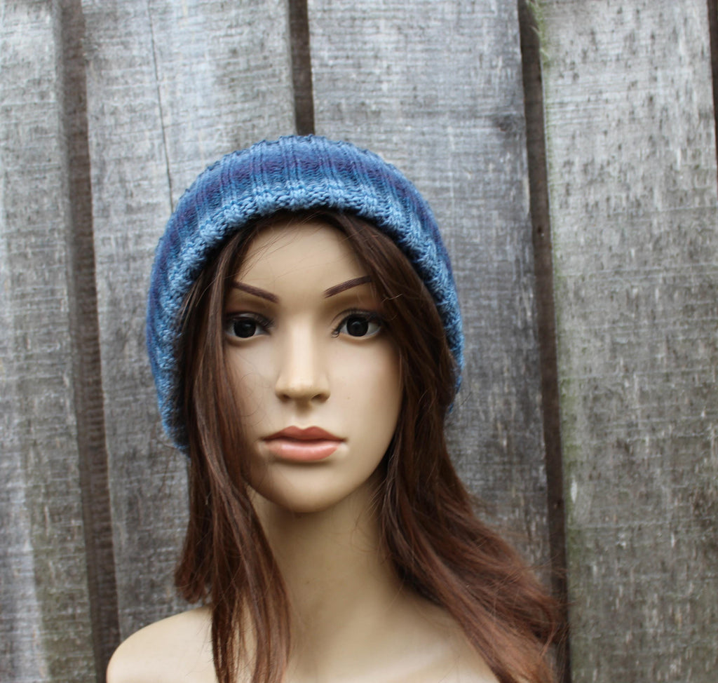 Mannequin head wearing a blue knitted beanie against a wooden panel background