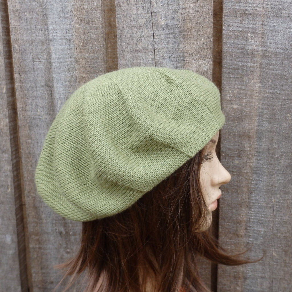 Person wearing a green knitted beret against a wooden fence background