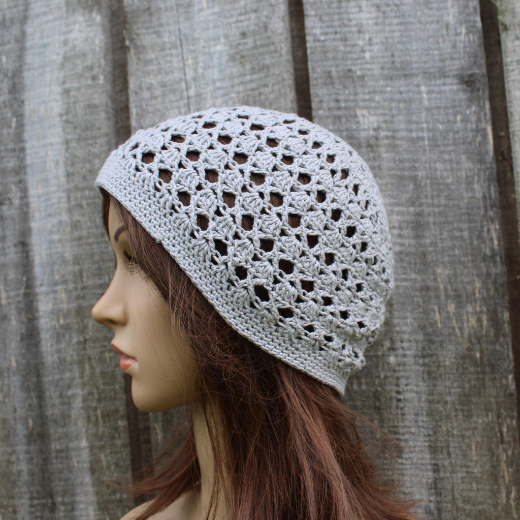 Mannequin head wearing a gray crochet beanie against a wooden background