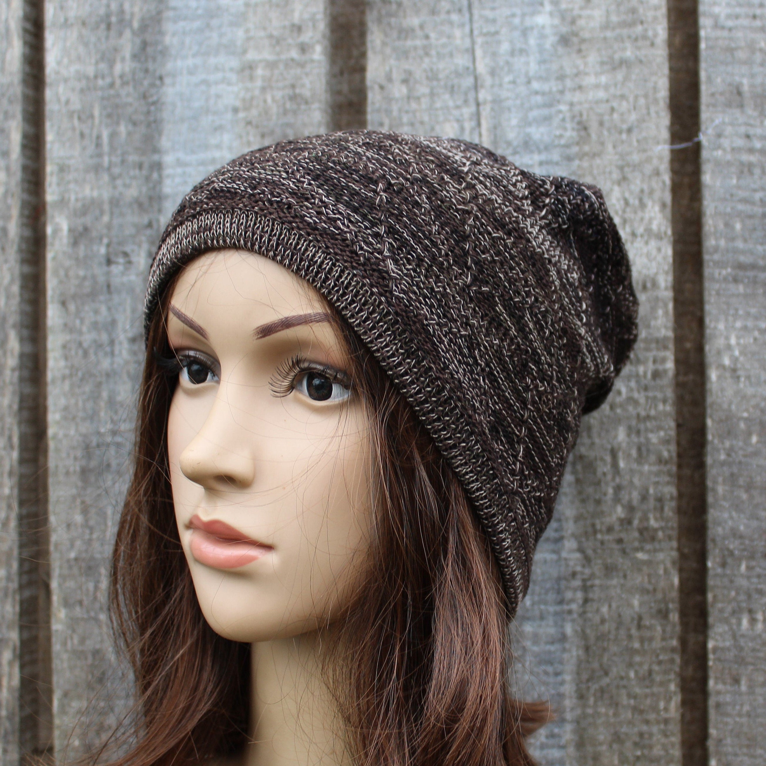 Mannequin head wearing a brown knit beanie against a wooden panel background