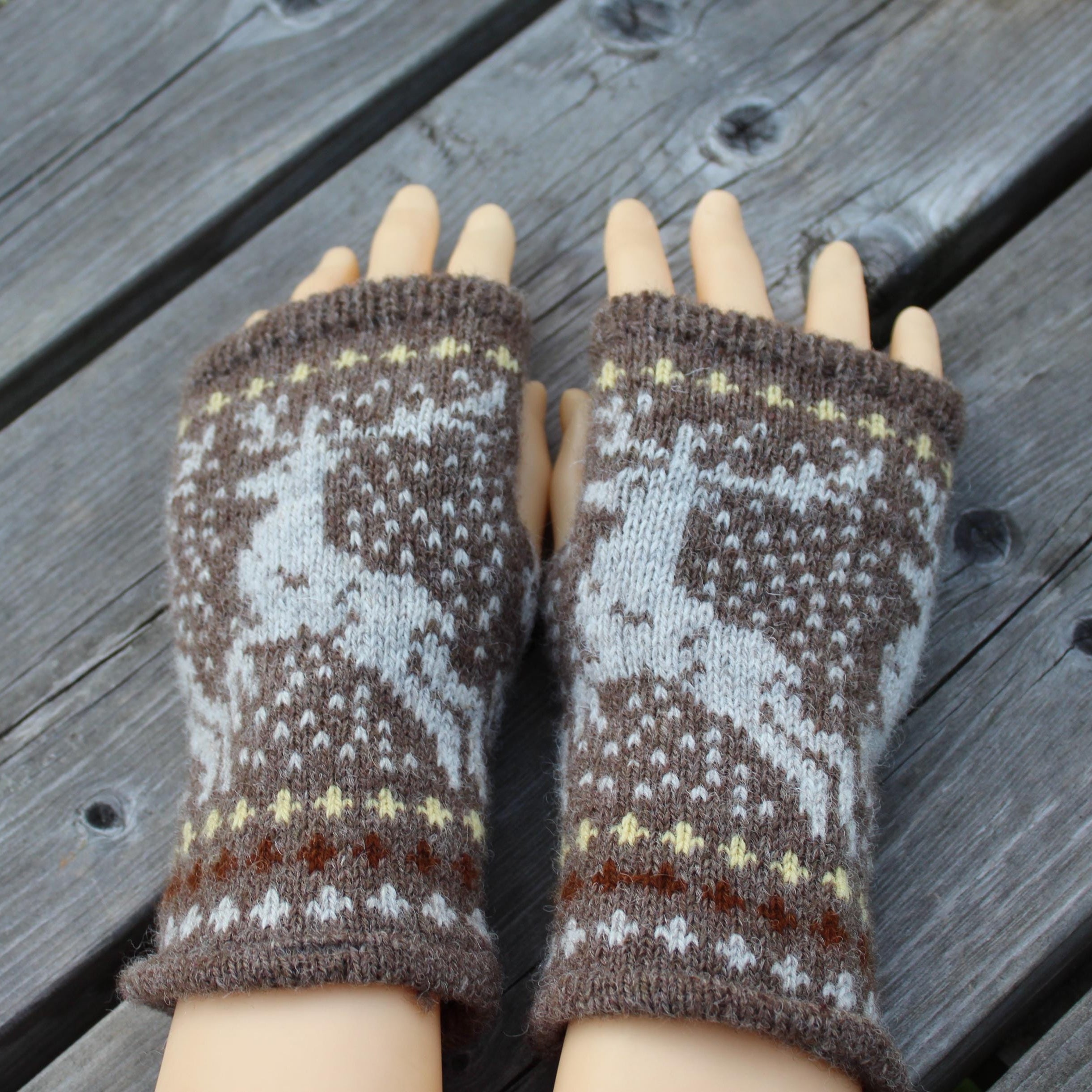 Pair of knitted fingerless gloves with a pattern on a wooden surface