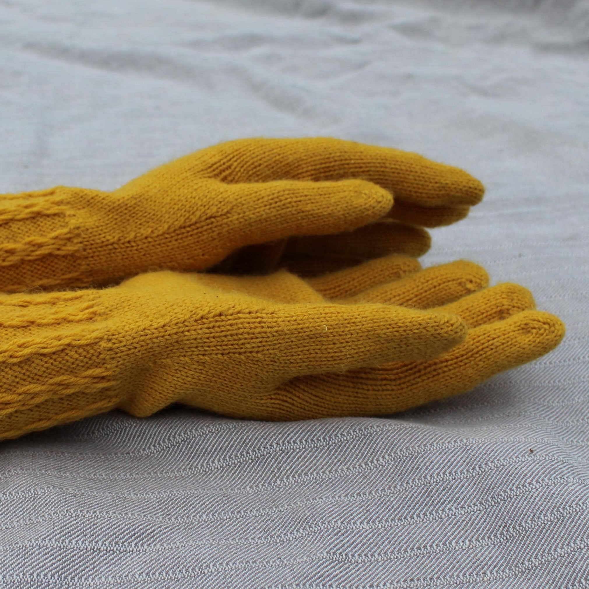 Yellow knitted gloves on a gray surface
