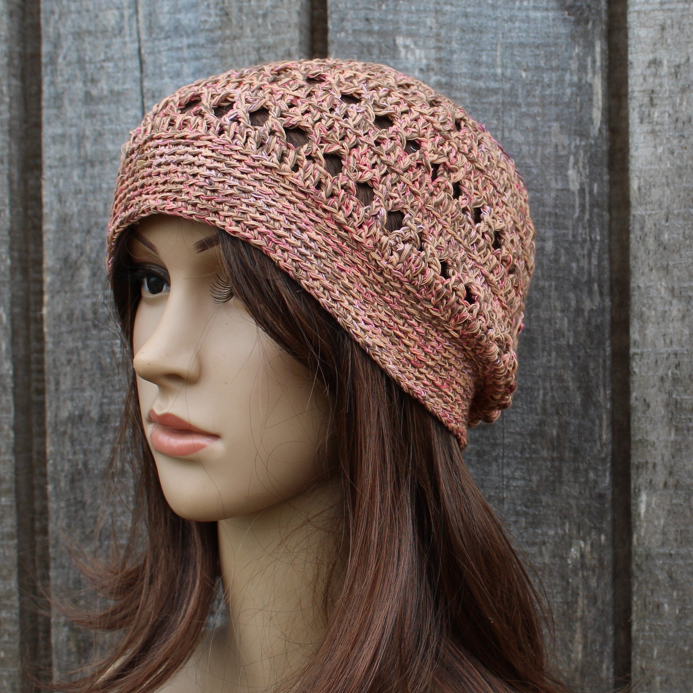 Mannequin head wearing a orange crochet hat against a wooden background