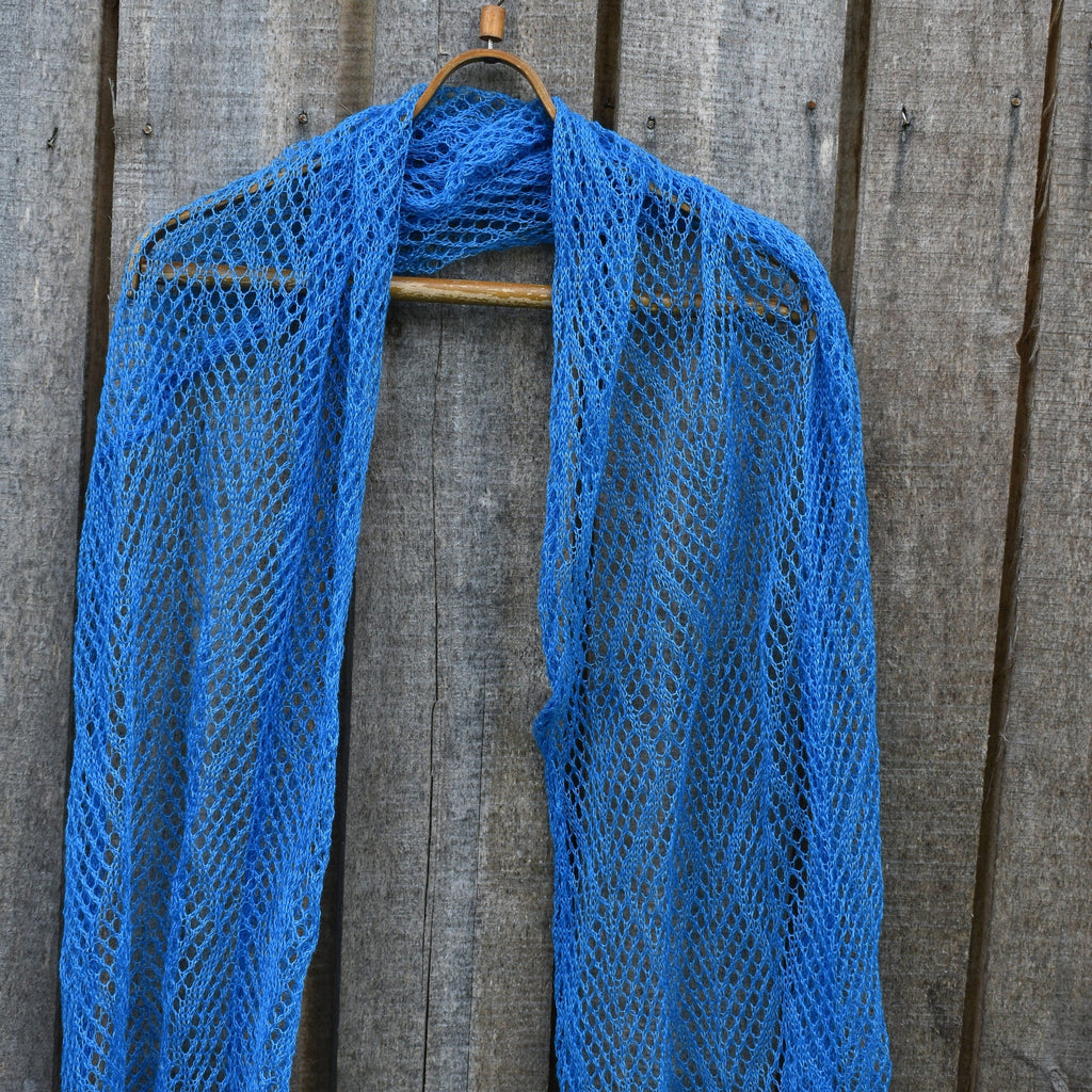 Flax knitted shawl on a wooden hanger against a wooden background