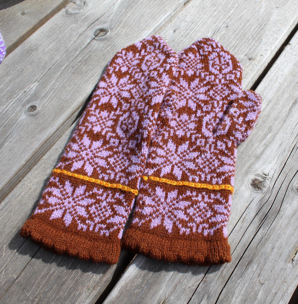 Pair of brown and pink patterned mittens on a wooden surface