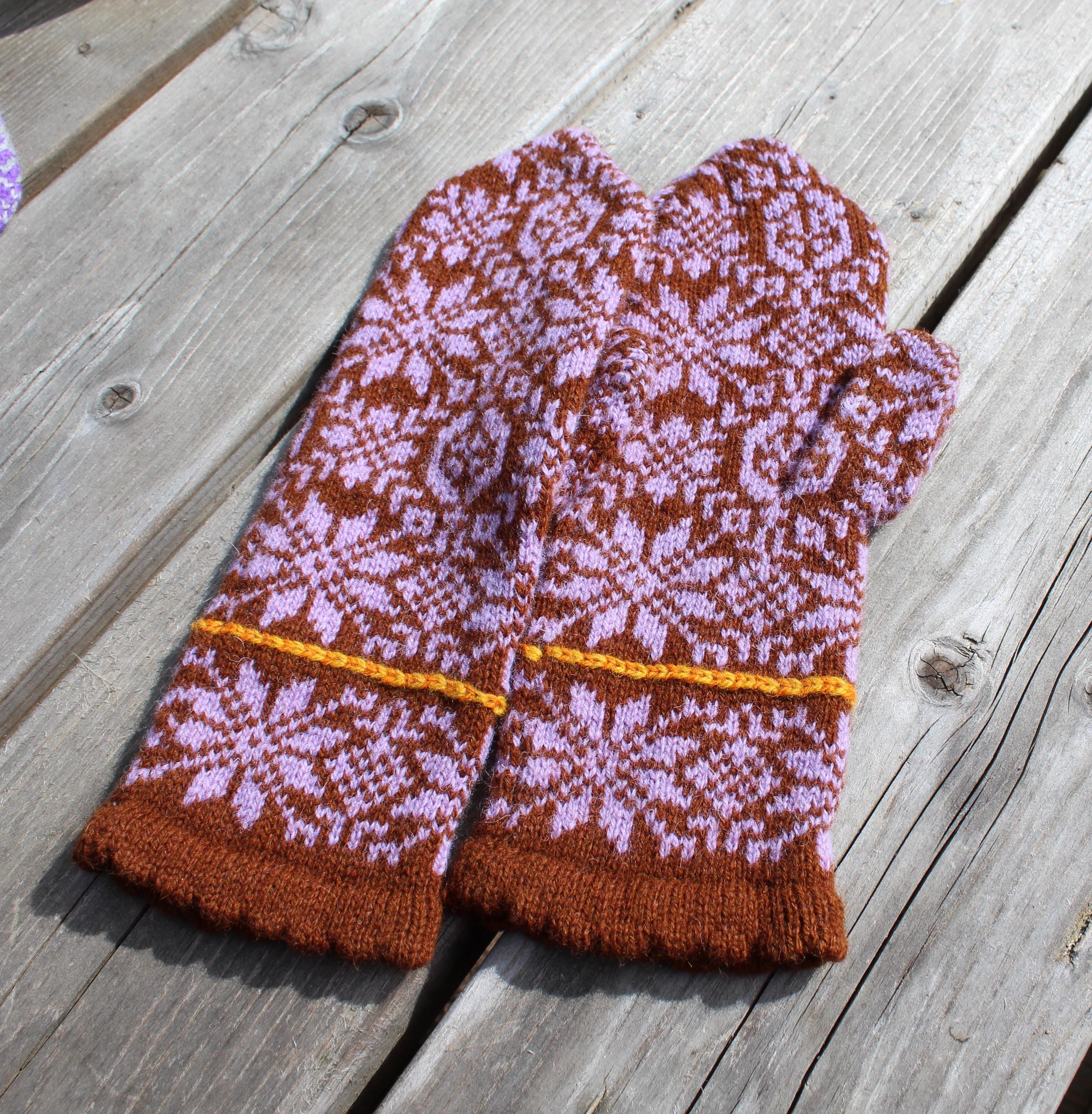 Pair of brown and pink patterned mittens on a wooden surface