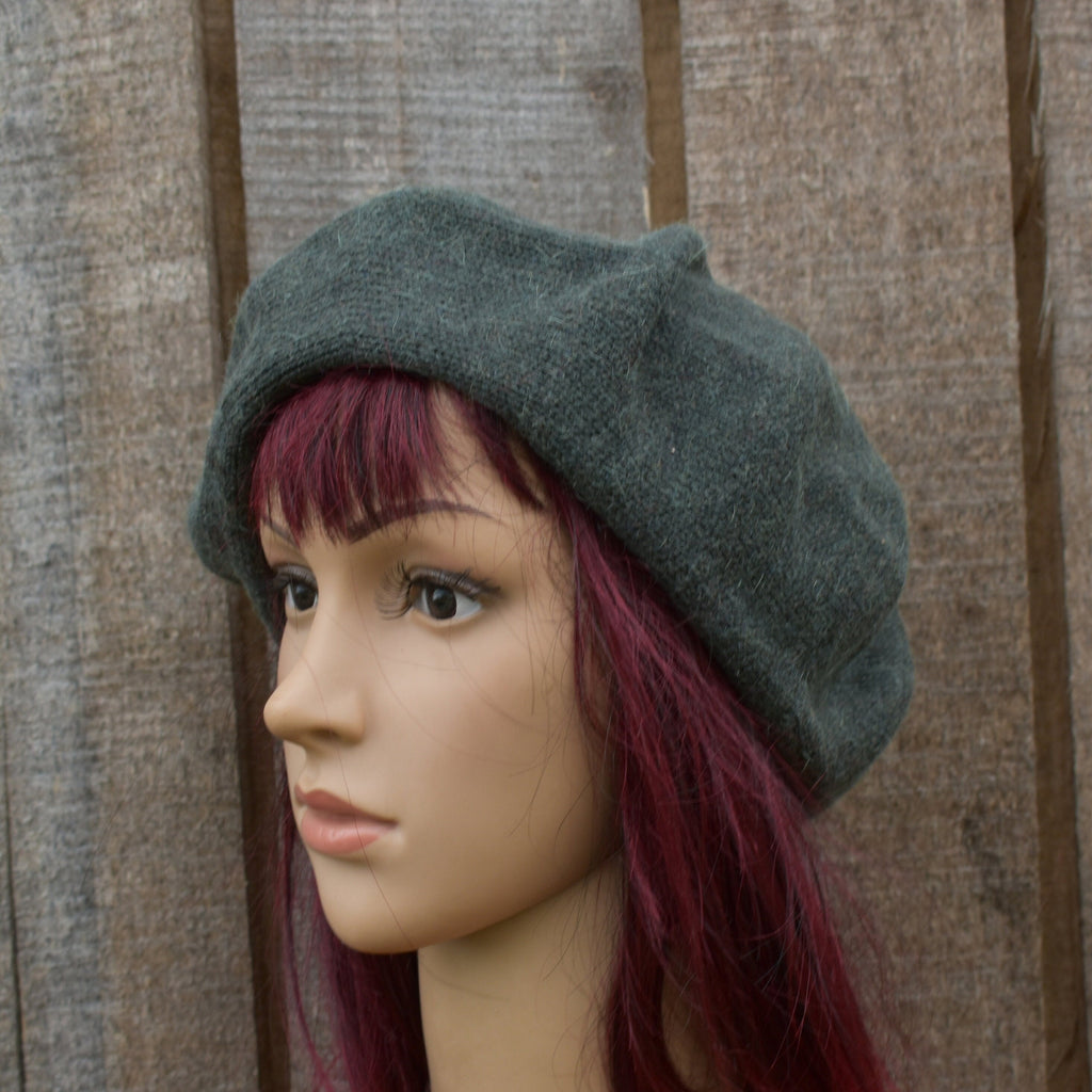 Mannequin head wearing a grey beret against a wooden background