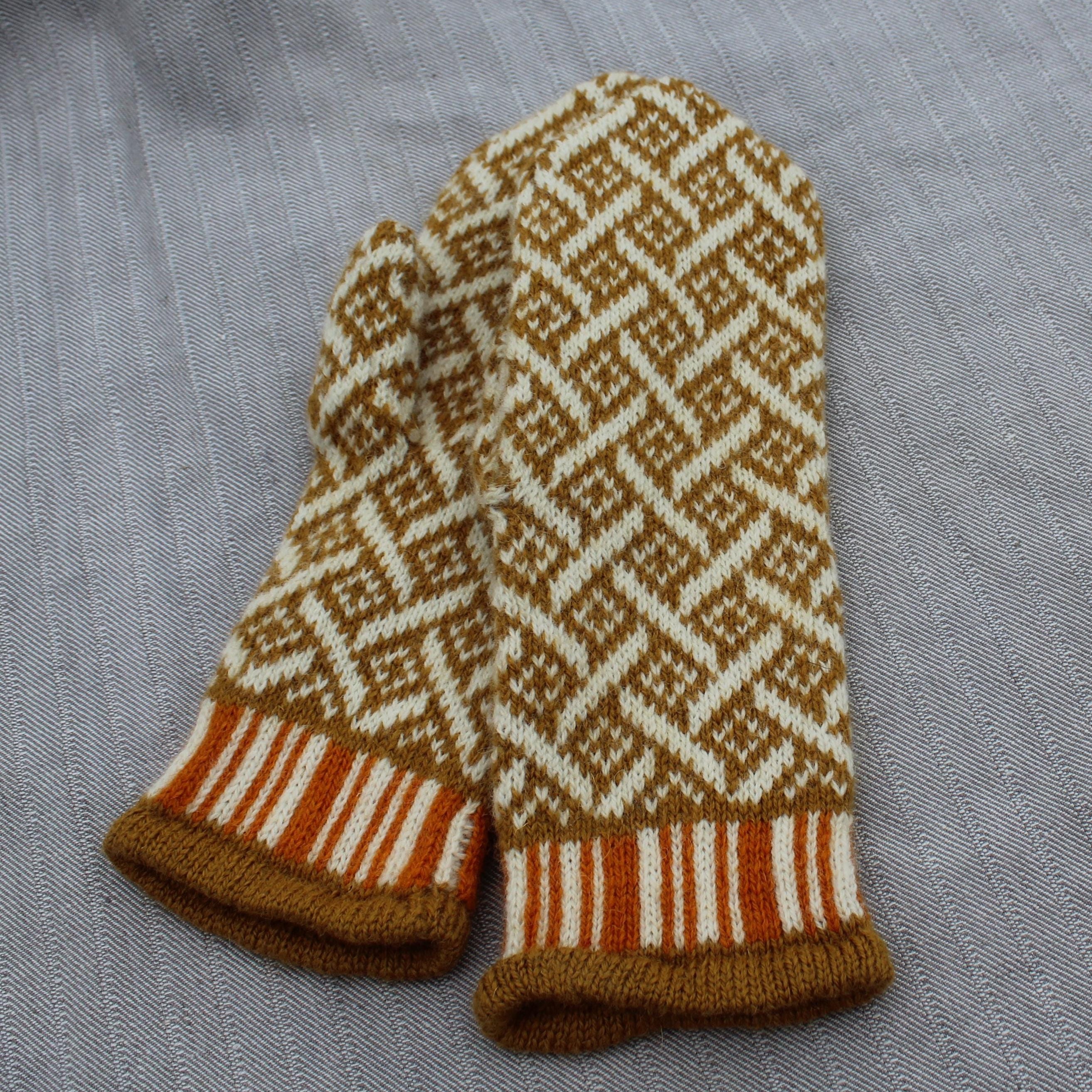 Pair of knitted mittens with a geometric pattern on a gray fabric background