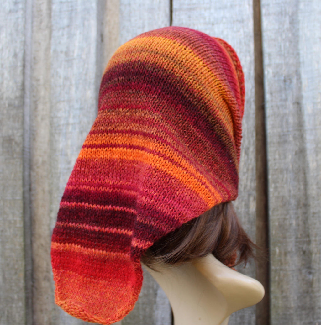 Knitted hat with red and orange gradient on a mannequin head against a wooden background