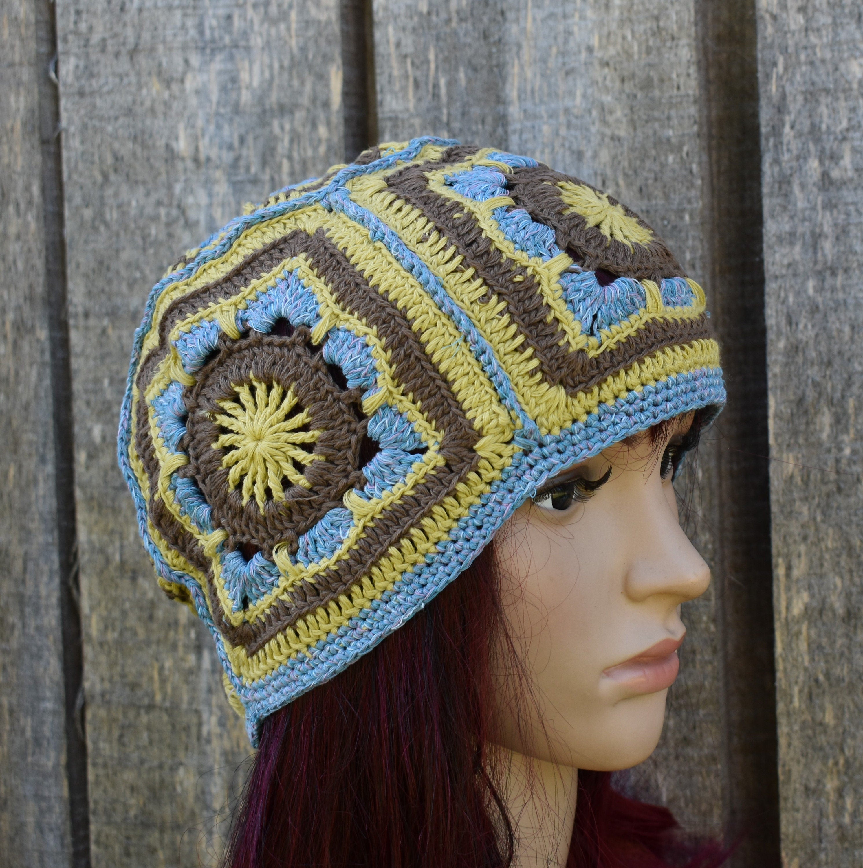 Crocheted hat with geometric pattern on a mannequin head against a wooden background