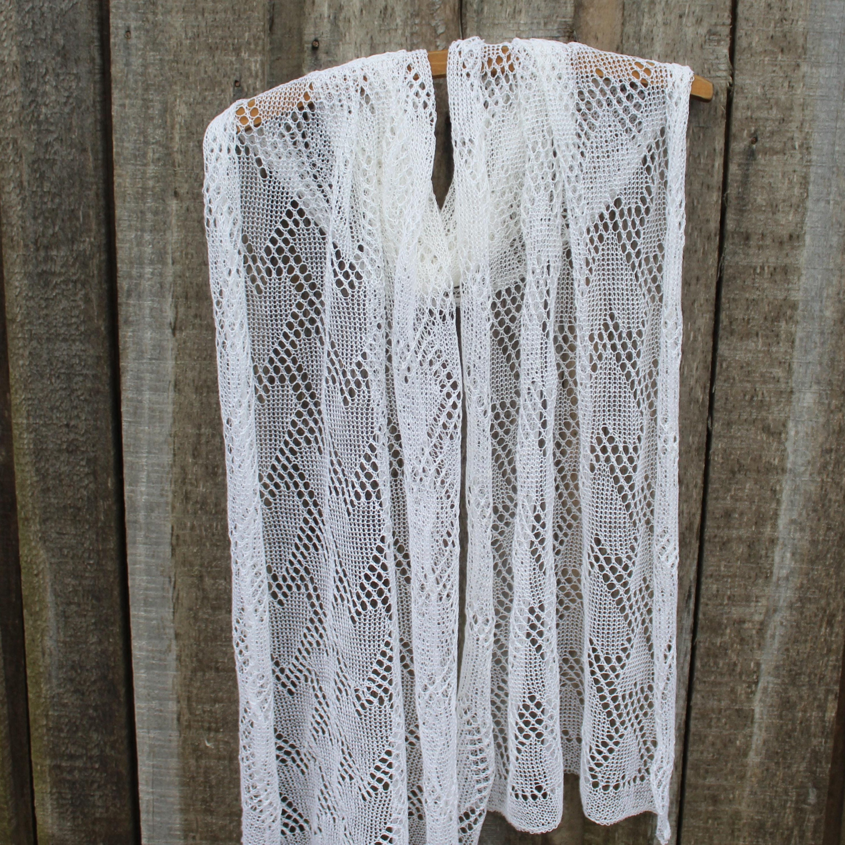 White lace shawl hanging on a wooden surface