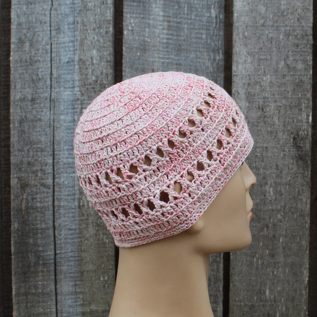 Pink crochet beanie on a mannequin head against a wooden background
