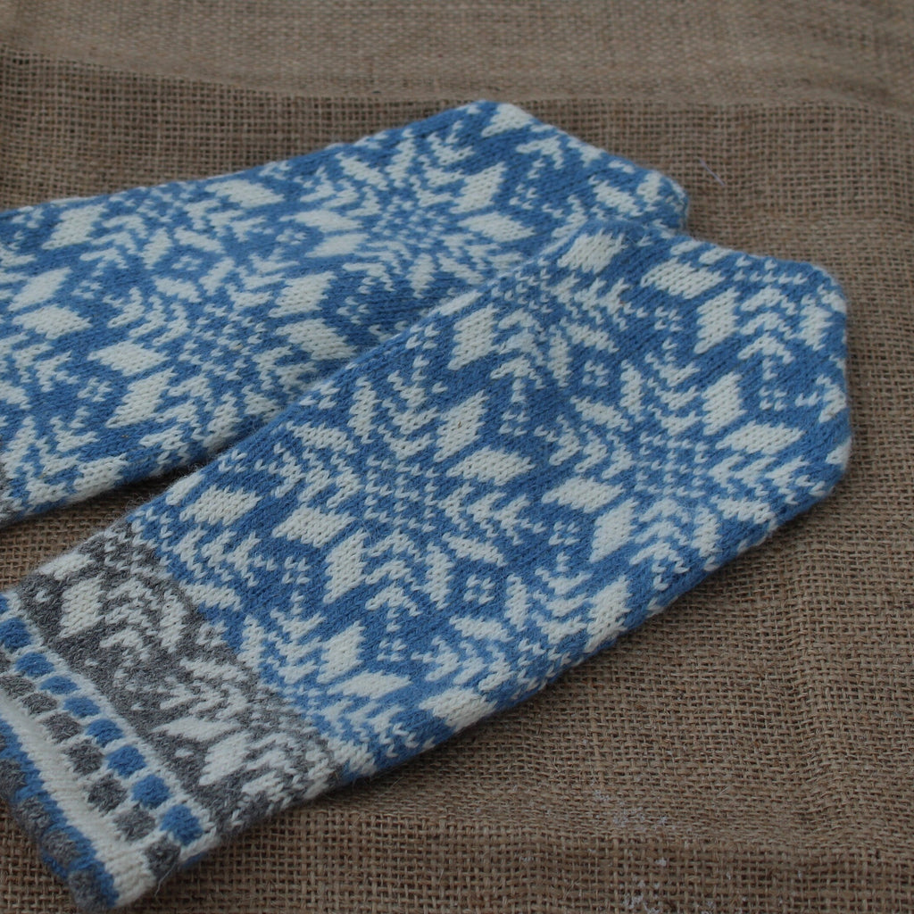 Pair of blue and gray patterned mittens on a brown fabric background