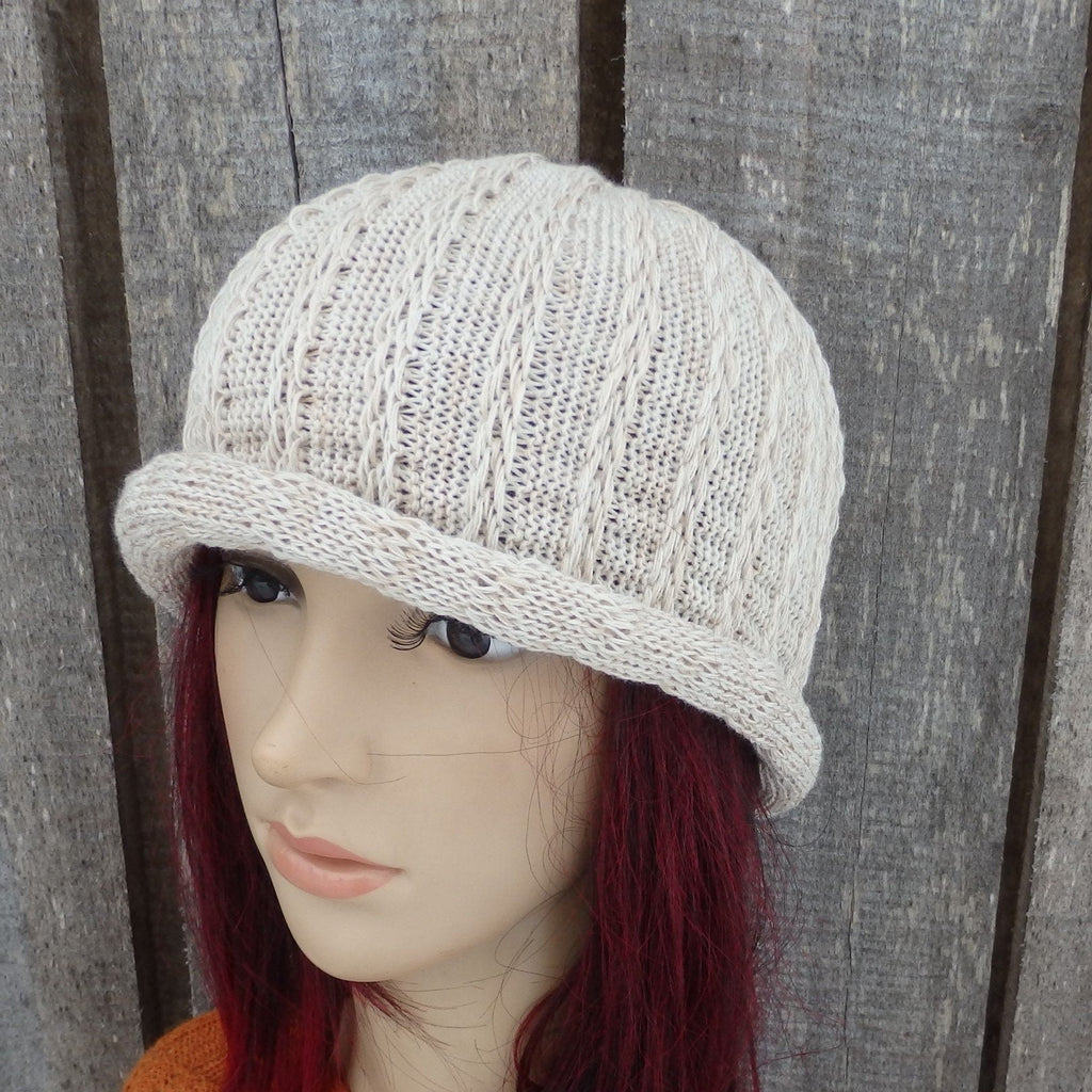 Knitted beige hat on a mannequin head against a wooden background