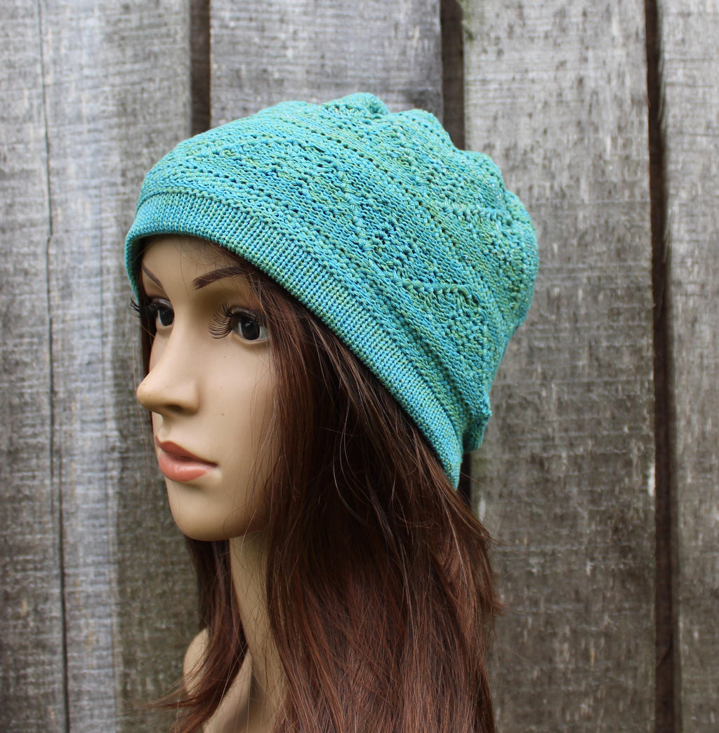Turquoise knitted hat on a mannequin head against a wooden background