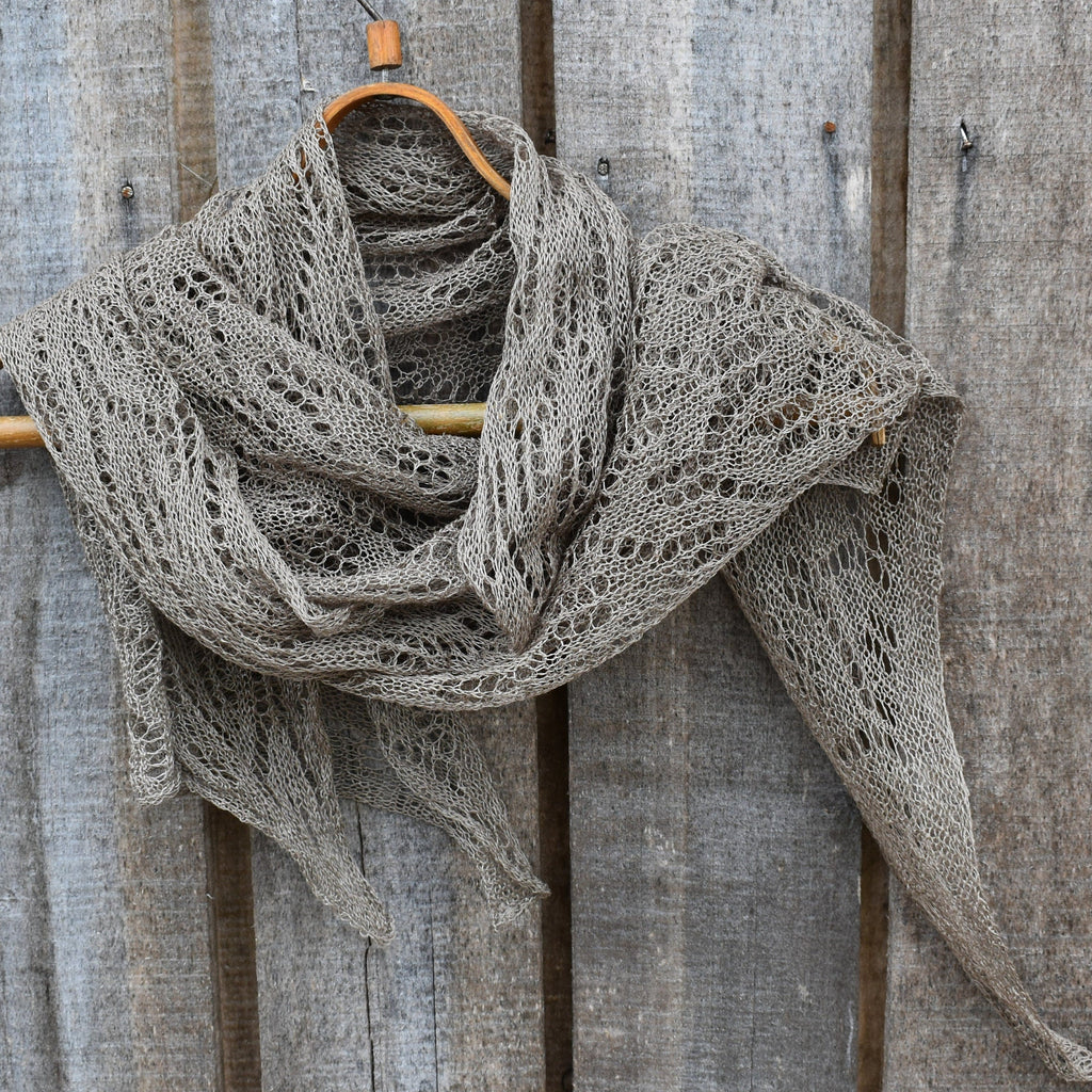 Knitted scarf draped over a wooden hanger against a rustic wooden background