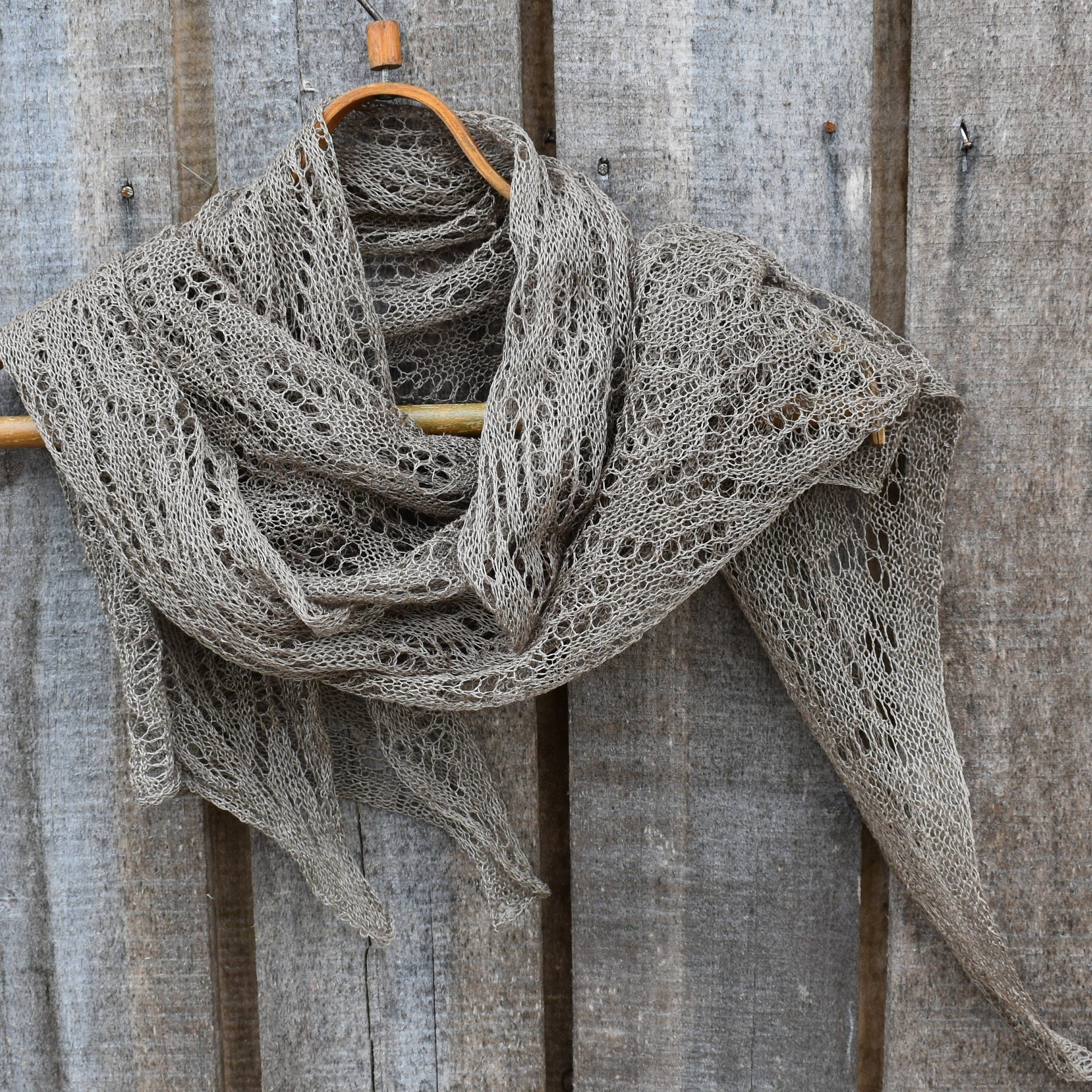 Knitted scarf draped over a wooden hanger against a rustic wooden background