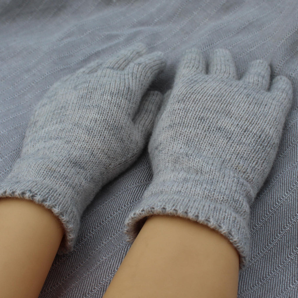 Gray knitted gloves on a person's hands with a gray fabric background