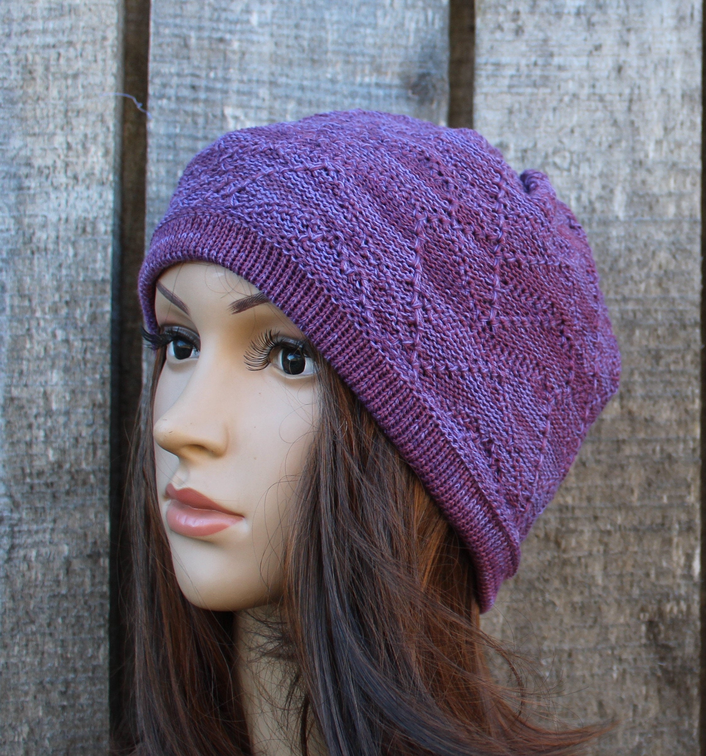 Purple knitted beanie on a mannequin head against a wooden background