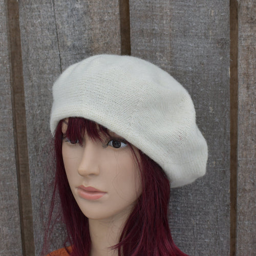 Mannequin head wearing a light gray knit hat against a wooden panel background