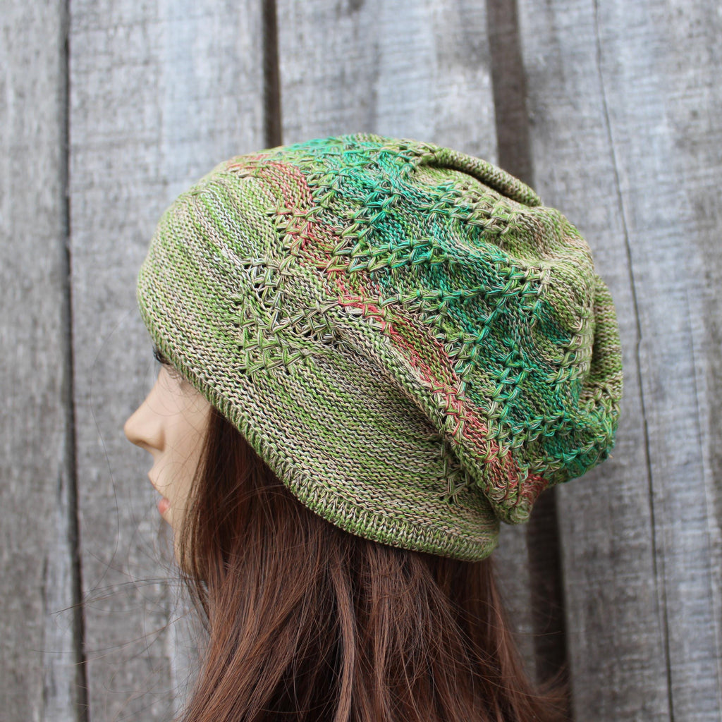 Green knitted hat worn by a person against a wooden background