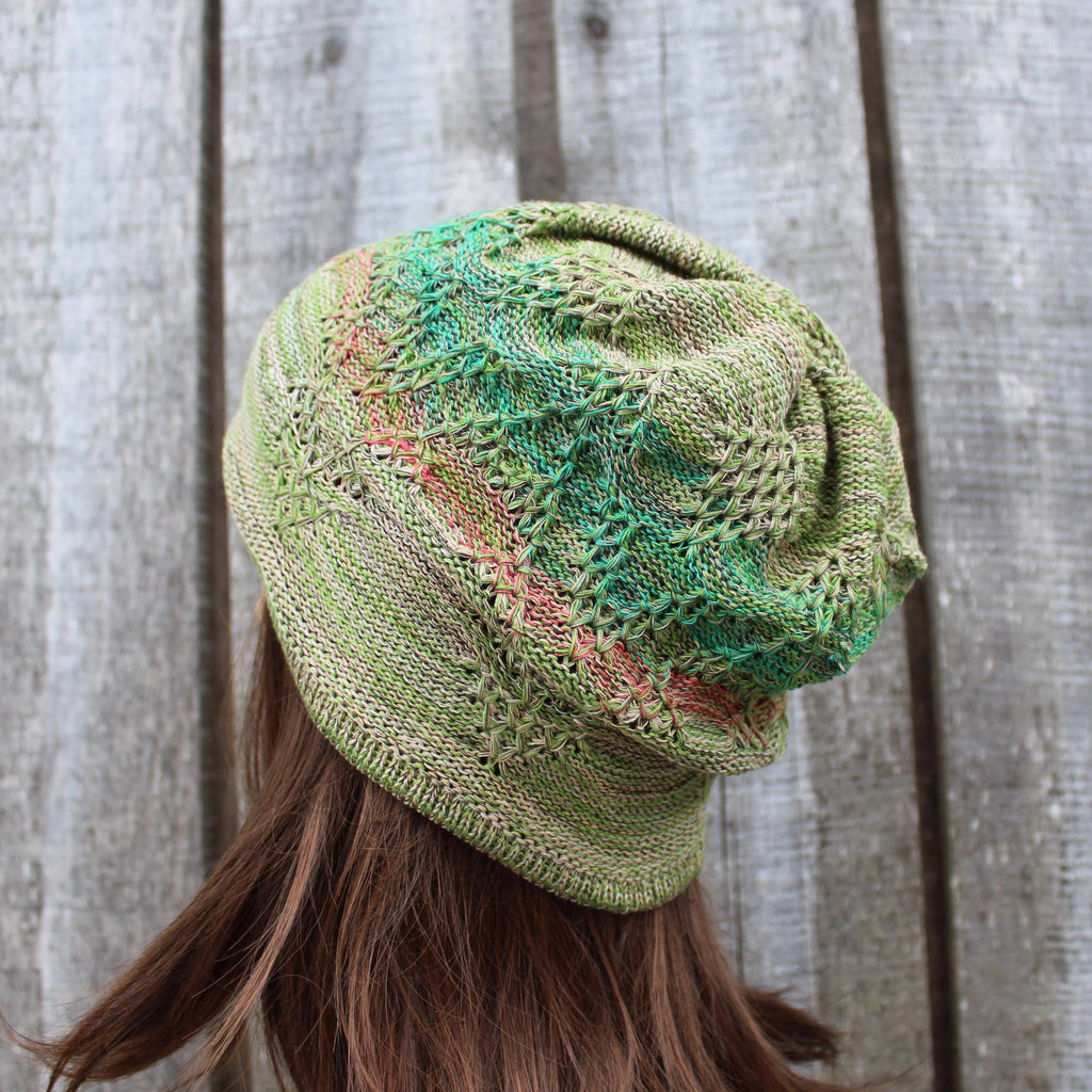 Green knitted beanie on a person against a wooden background