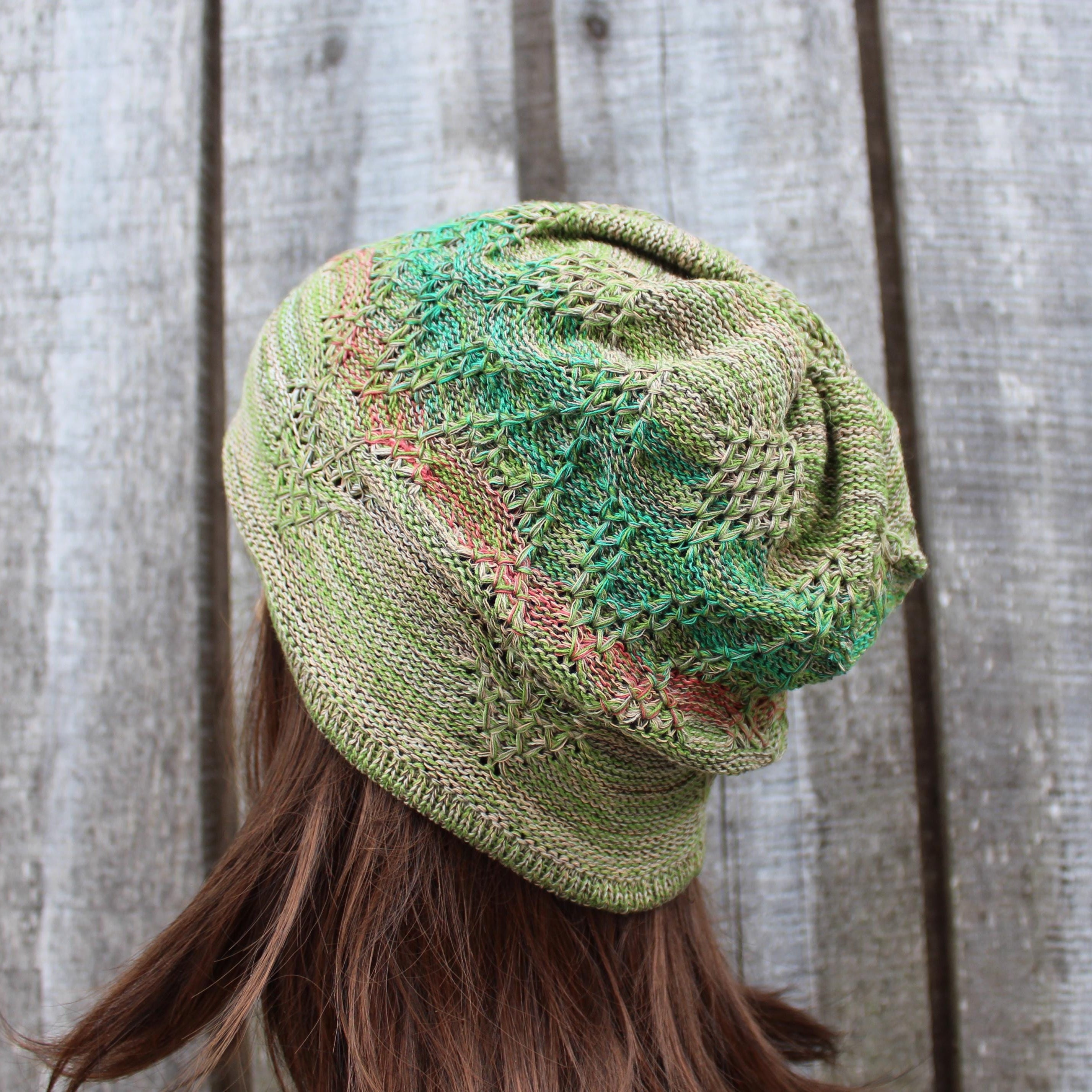 Green knitted beanie on a person against a wooden background