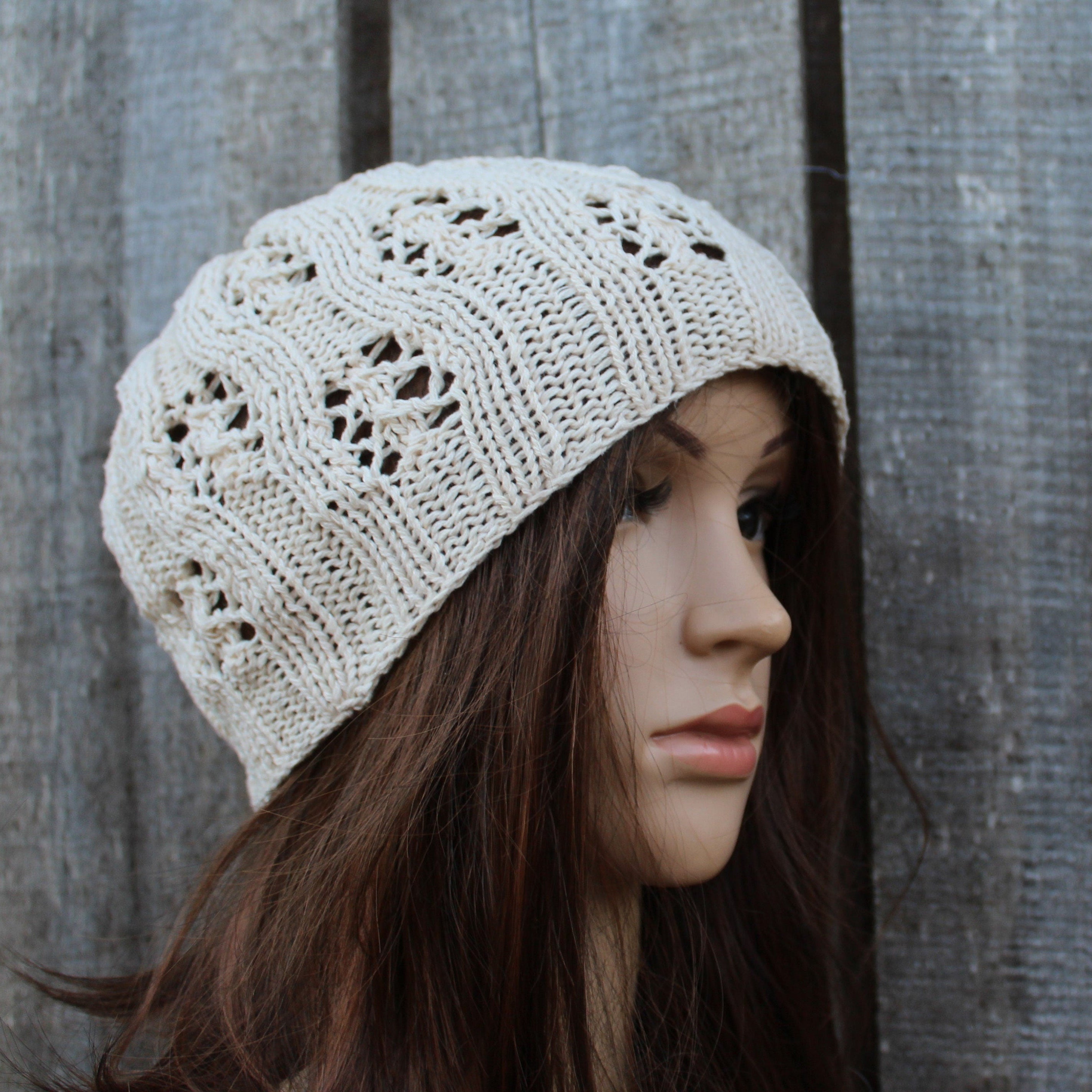 Beige knitted beanie worn by a mannequin against a wooden background