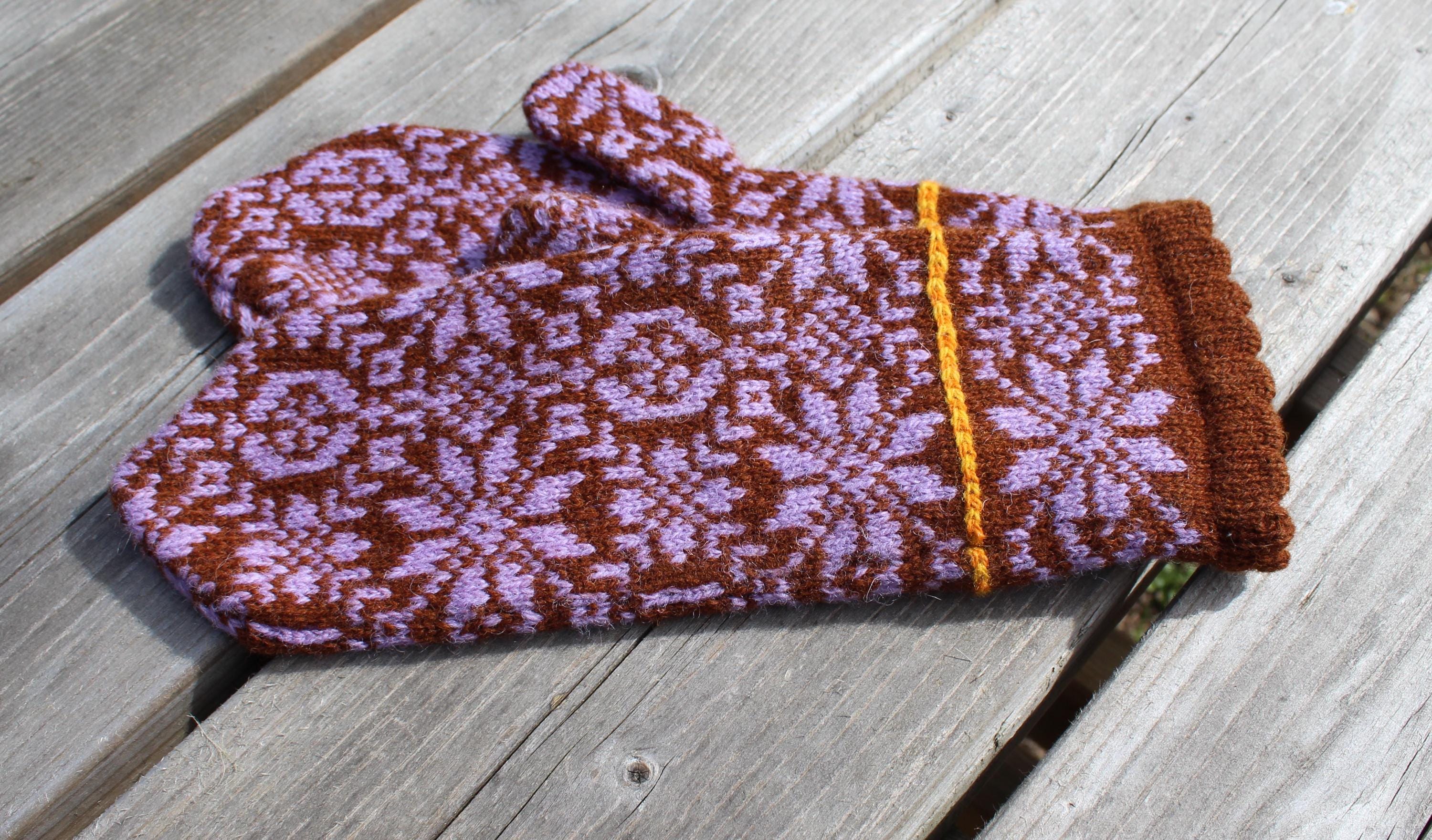 Knitted mittens with a floral pattern on a wooden surface
