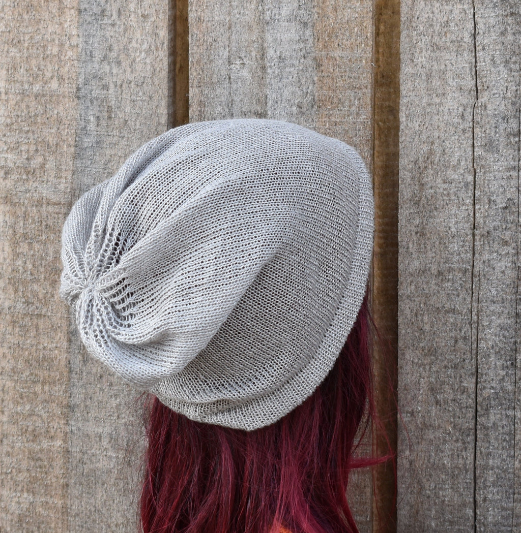 Gray knit beanie on a mannequin head with red hair against a wooden background