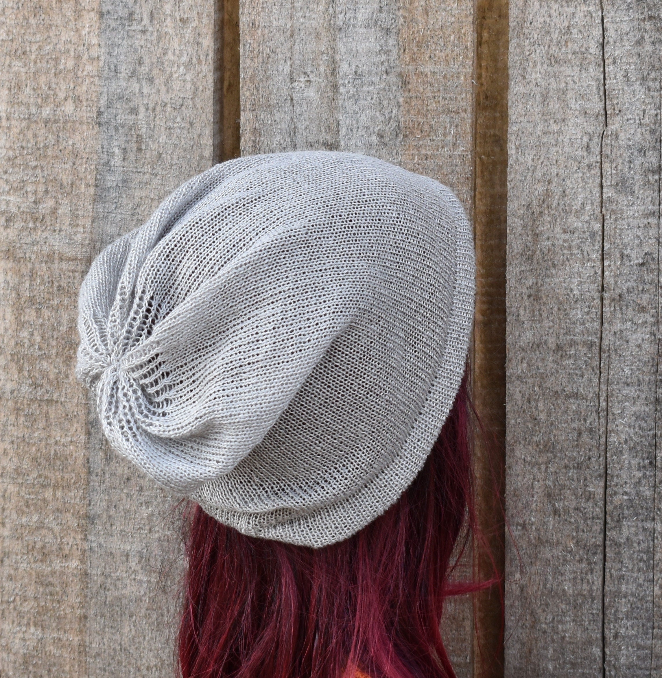 Gray knit beanie on a mannequin head with red hair against a wooden background