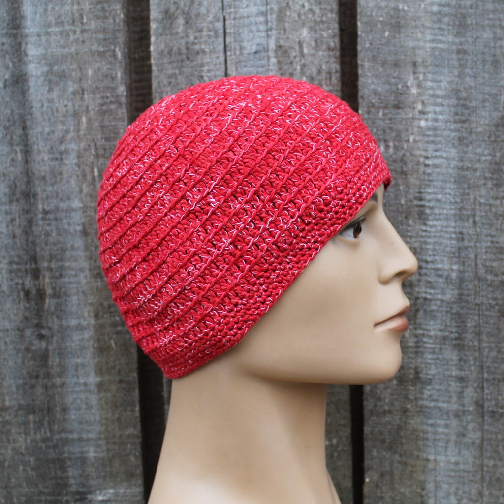 Red knitted beanie on a mannequin head against a wooden background