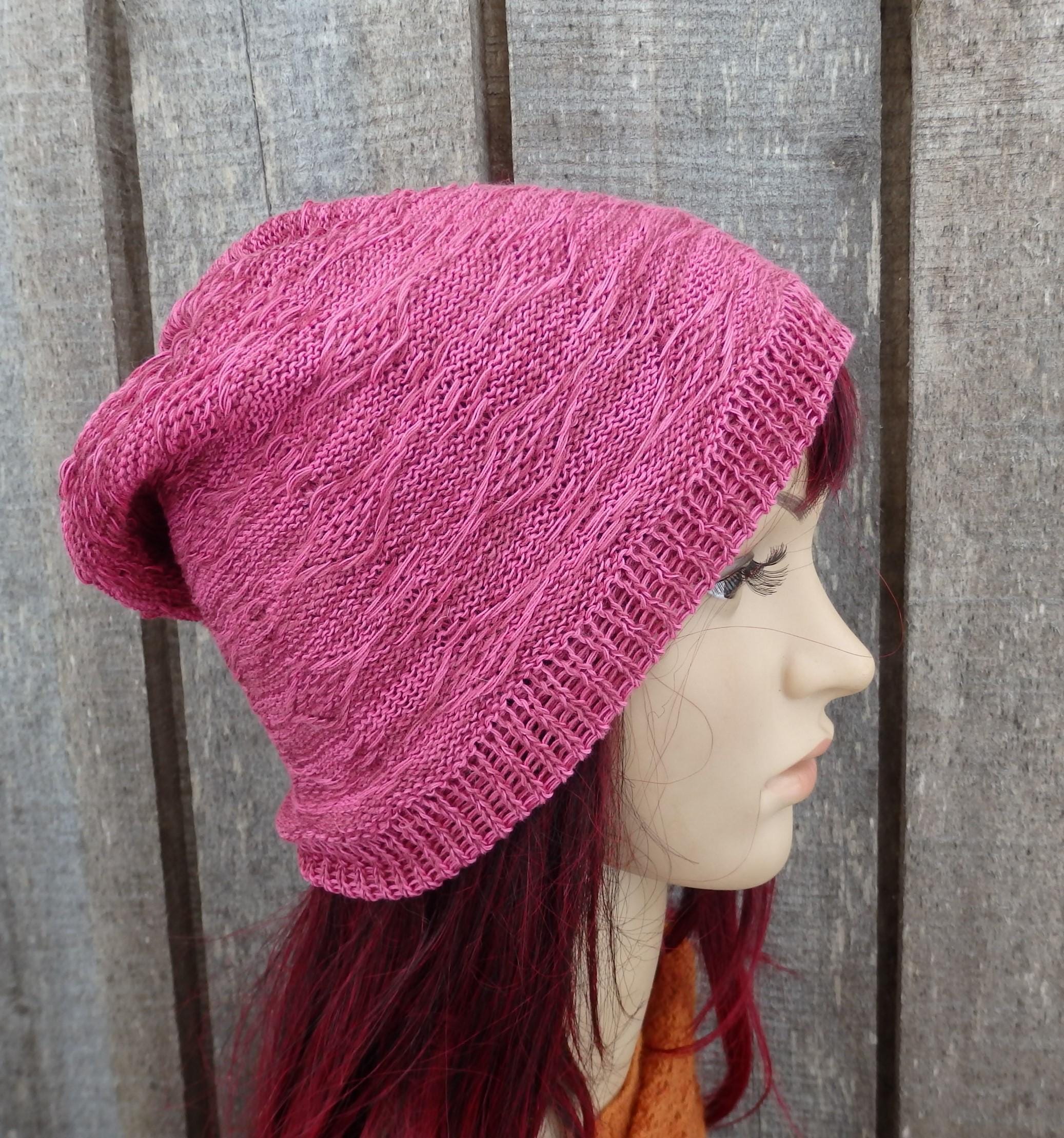 Mannequin head wearing a pink knitted hat against a wooden background