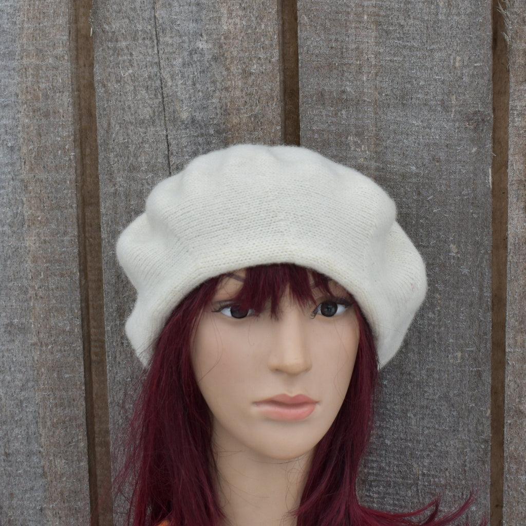 White knit beanie on a mannequin head against a wooden background