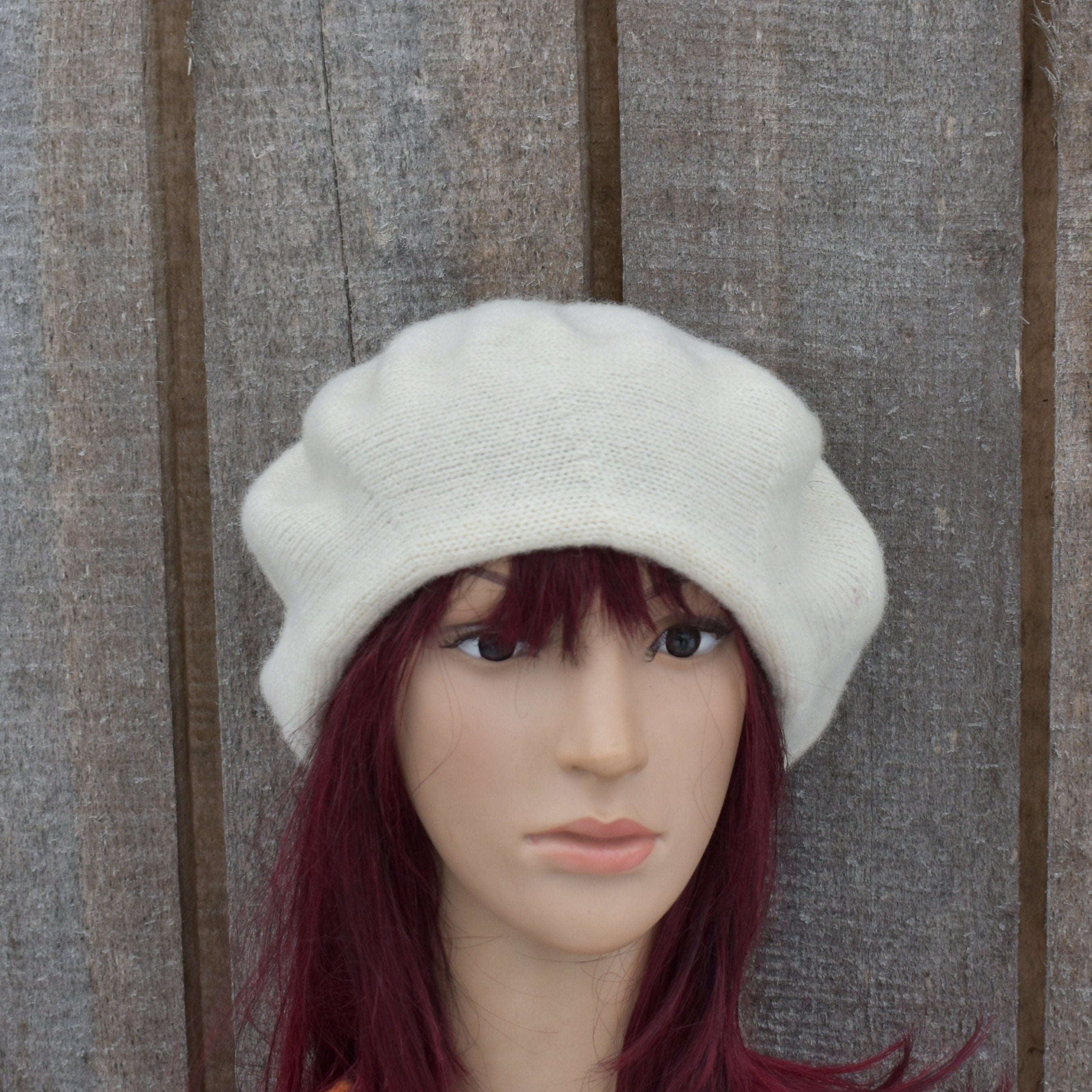 White knit beanie on a mannequin head against a wooden background