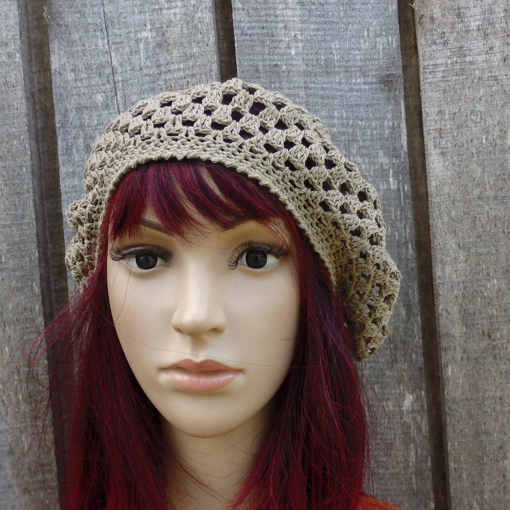 Mannequin head wearing a beige crochet hat against a wooden background